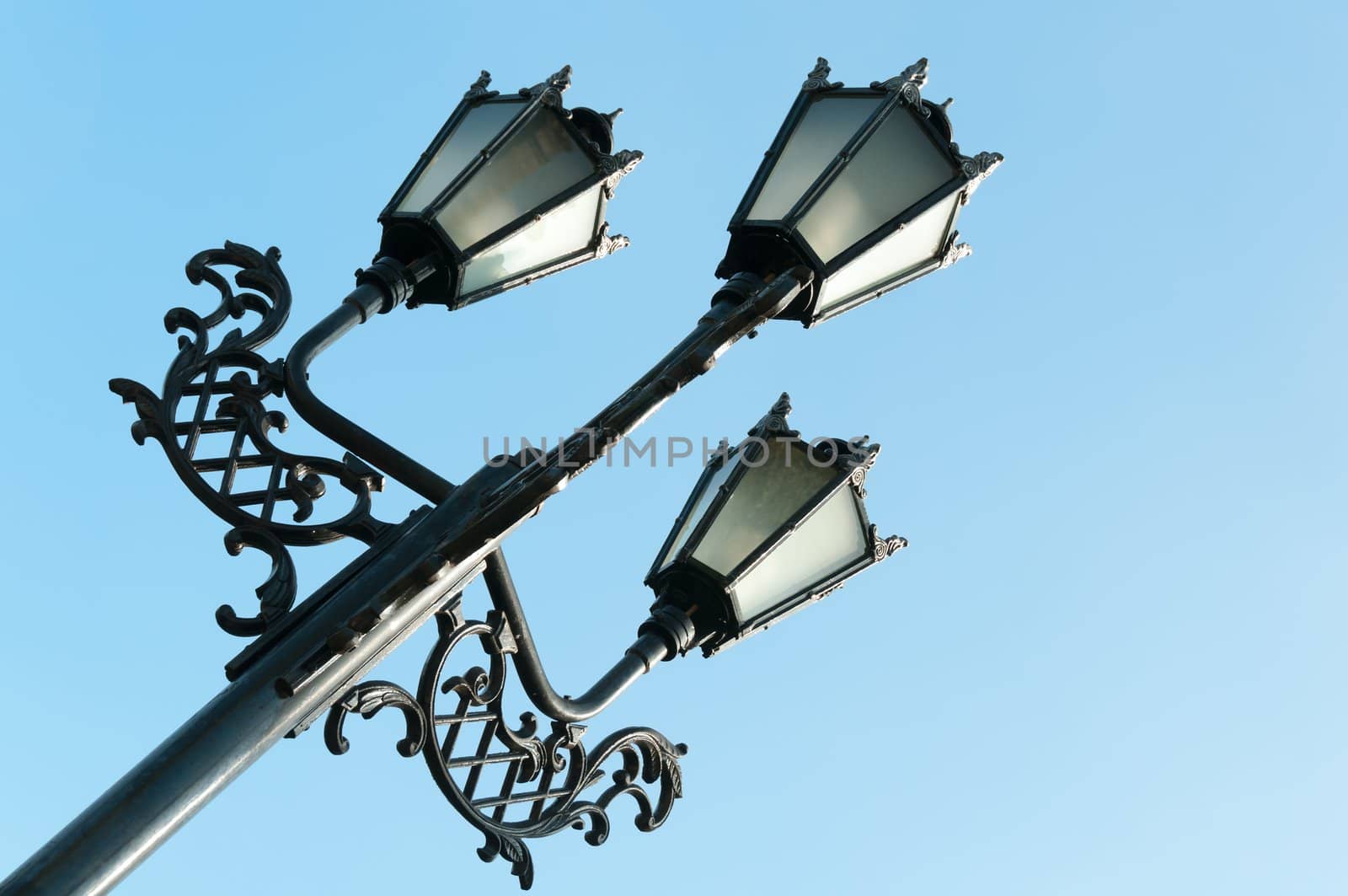 Antique metal street lamp with blue sky on background