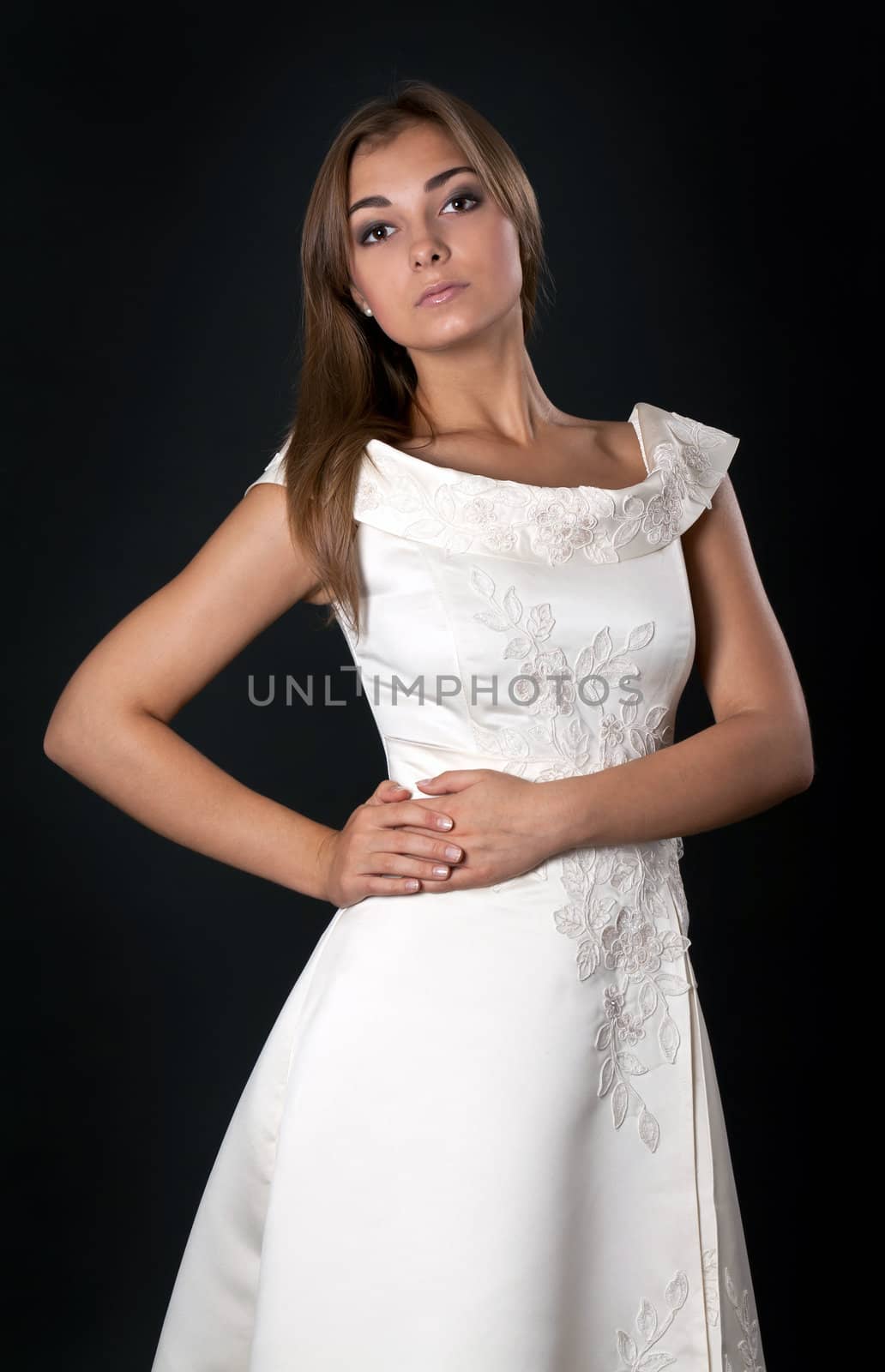 Beautiful girl in a white wedding dress in the studio on a black background