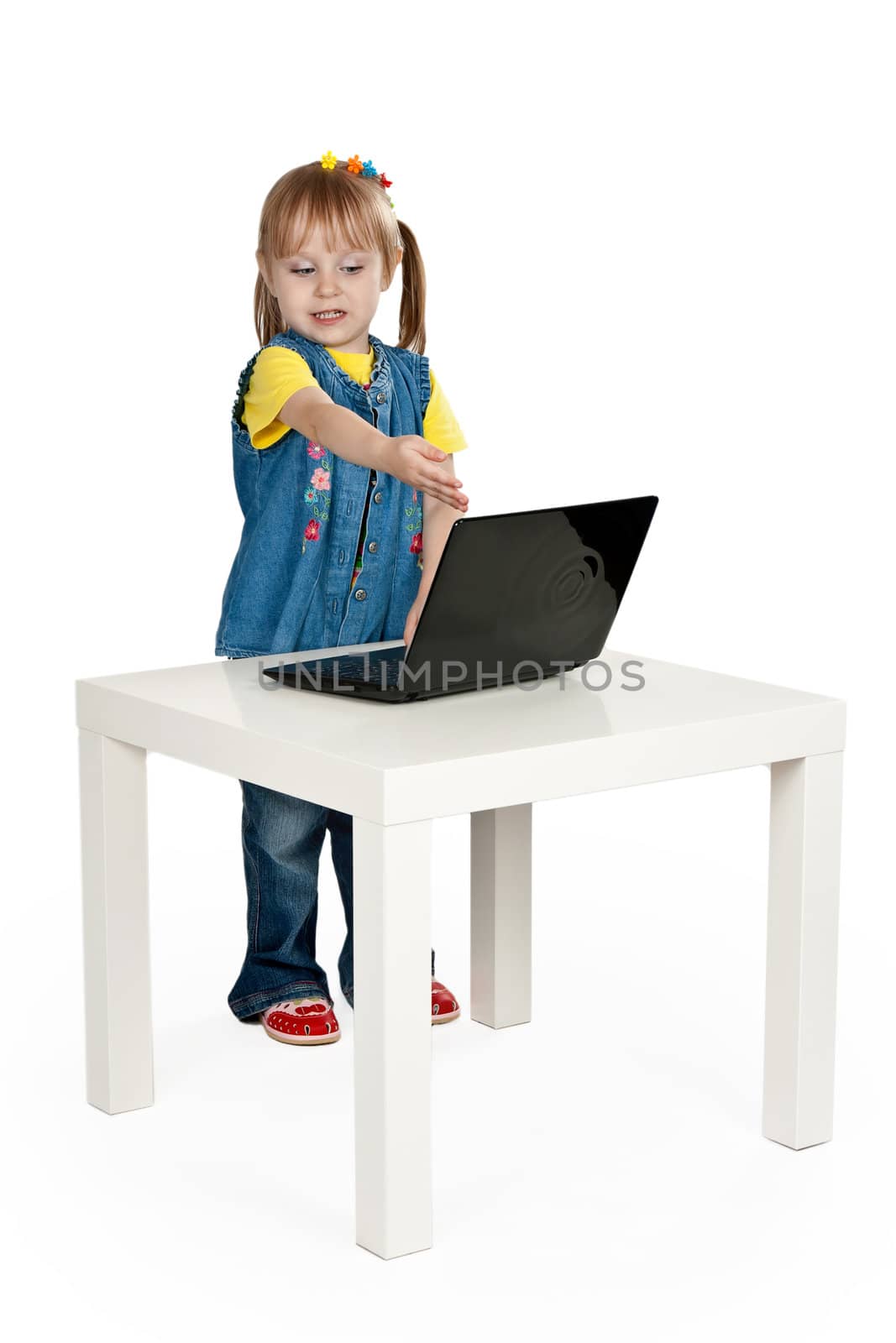 little girl with a laptop at a table on a gray background