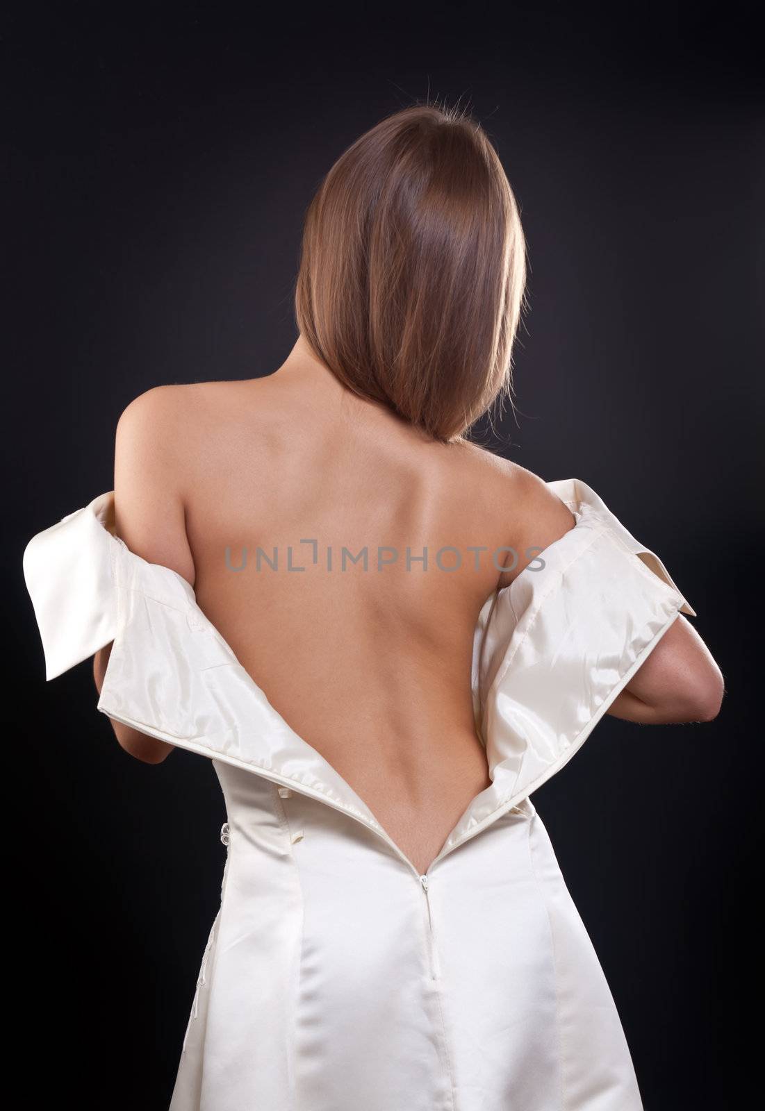 pretty girl with bare back in the studio on a black background