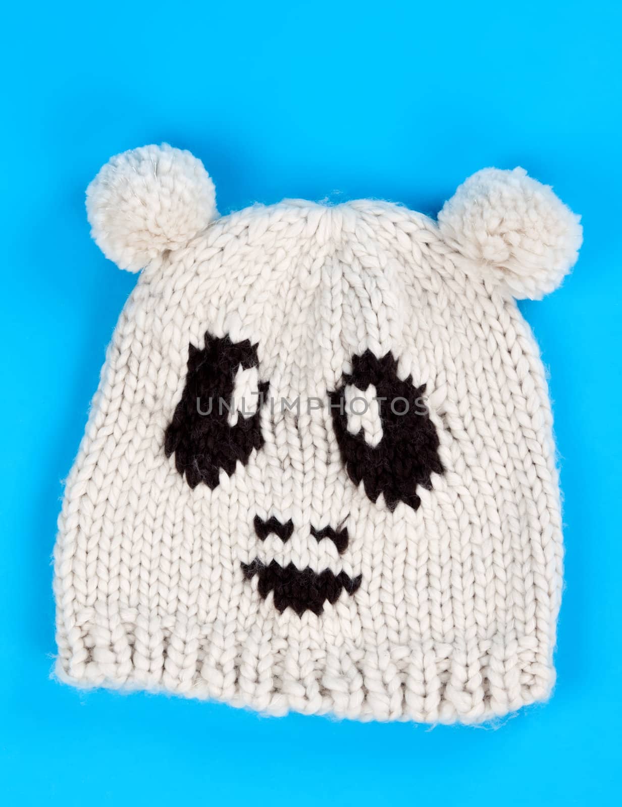 knitted wool hat with a pattern of little faces on a blue background
