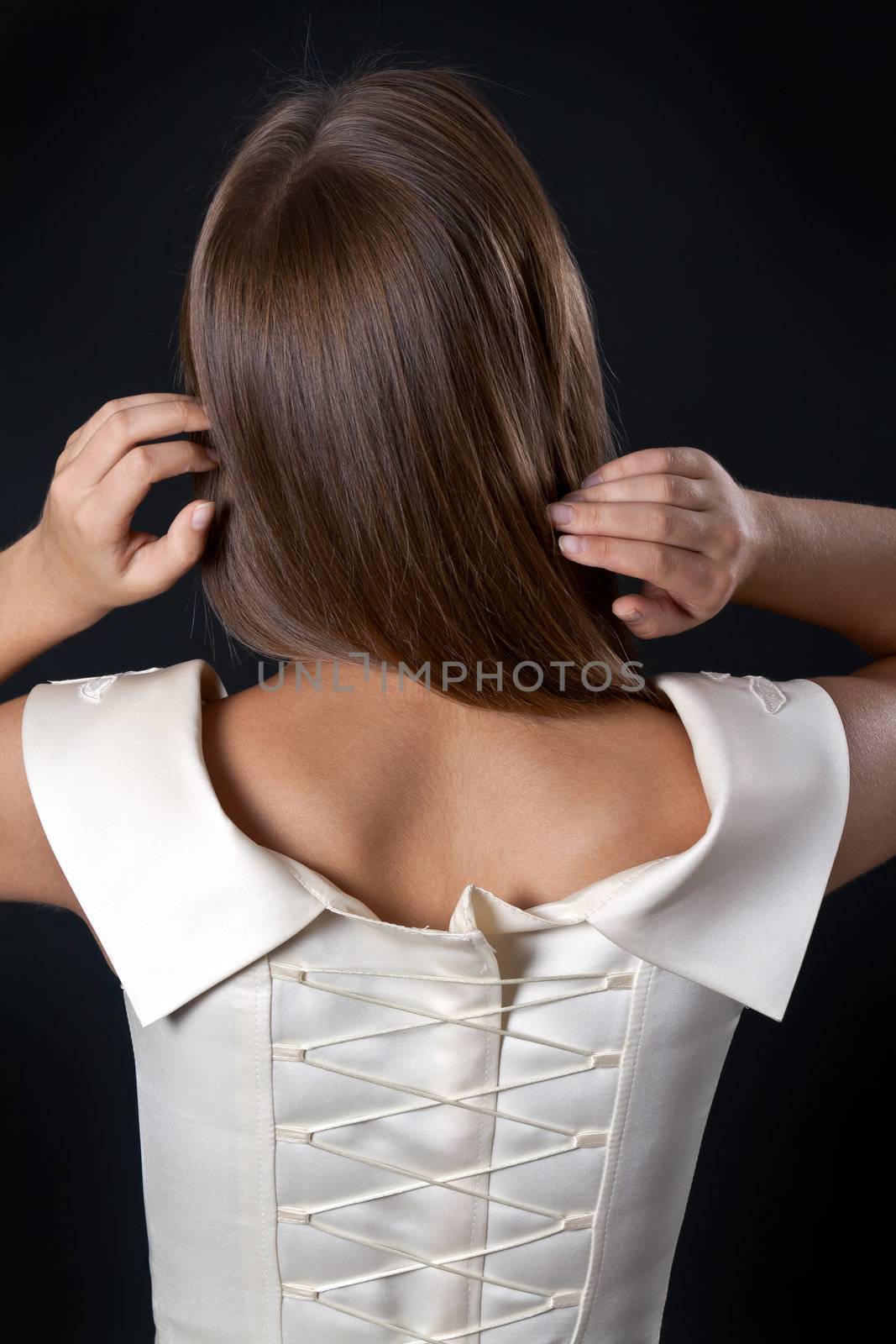 Beautiful slim girl in a wedding dress with a corset back in the studio on a black background