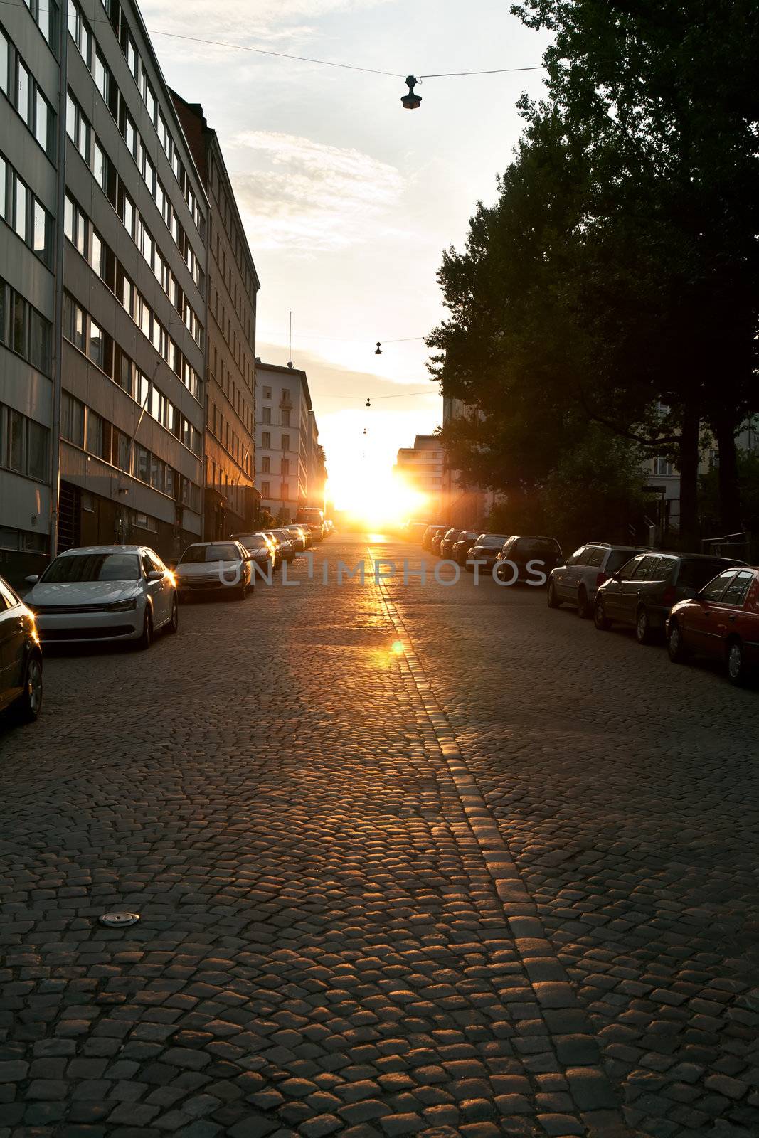 European narrow street with parked cars in the sunset light of the sun