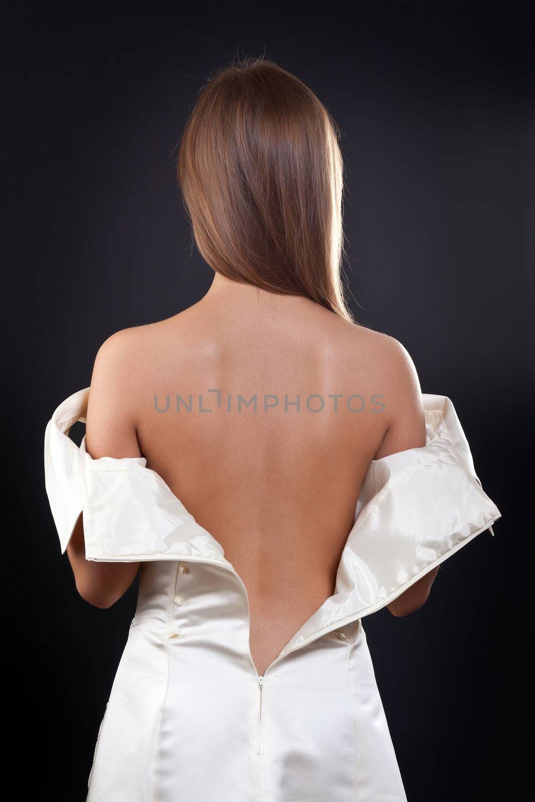 pretty girl with bare back in the studio on a black background