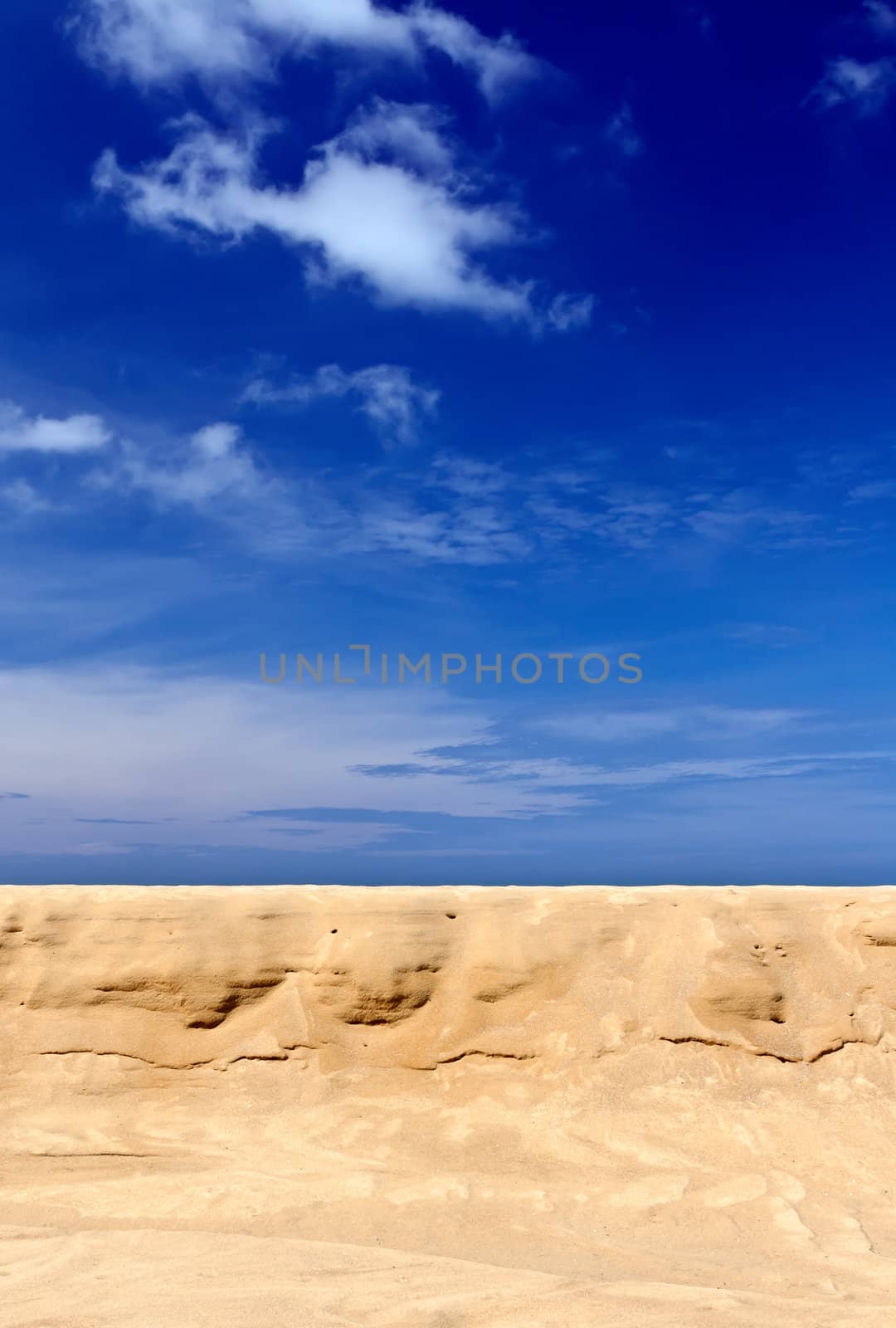 Tropical yellow sand against the blue sky with clouds