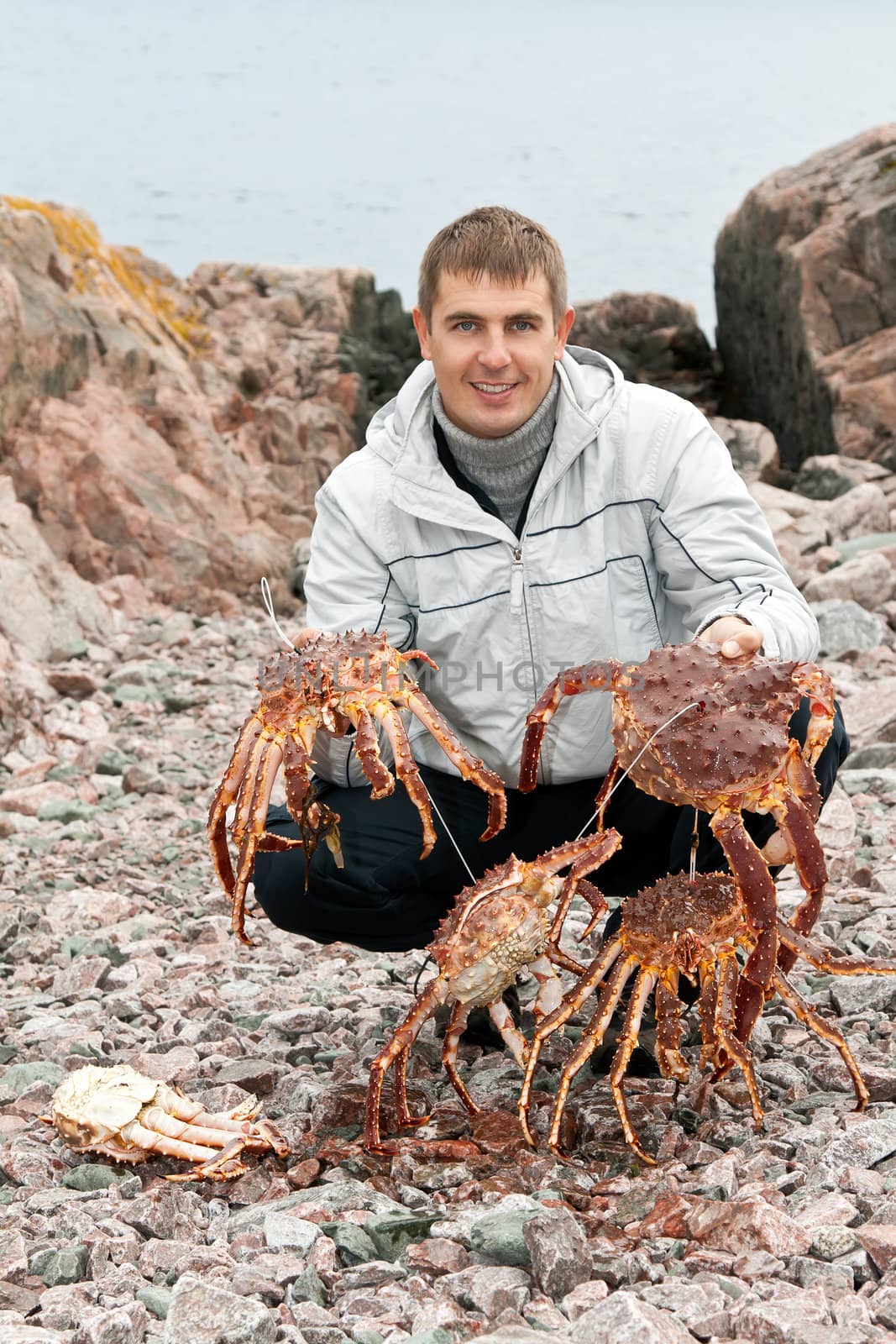 man with crabs in the Barents Sea coast, after a successful fishing