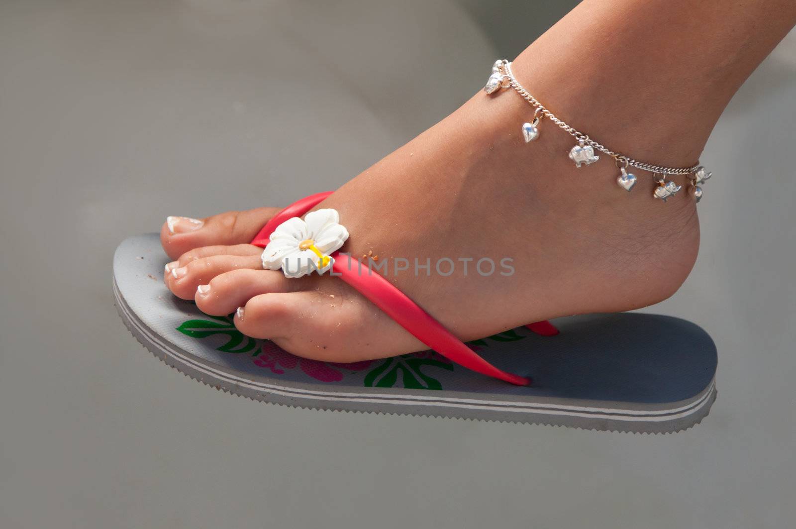Women's leg with a bracelet in thong on a gray background