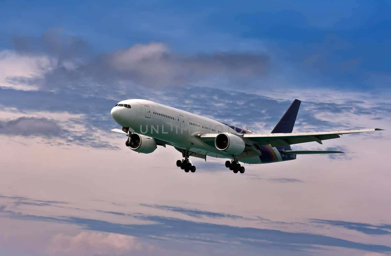 passenger plane comes in to land on a blue sky with clouds