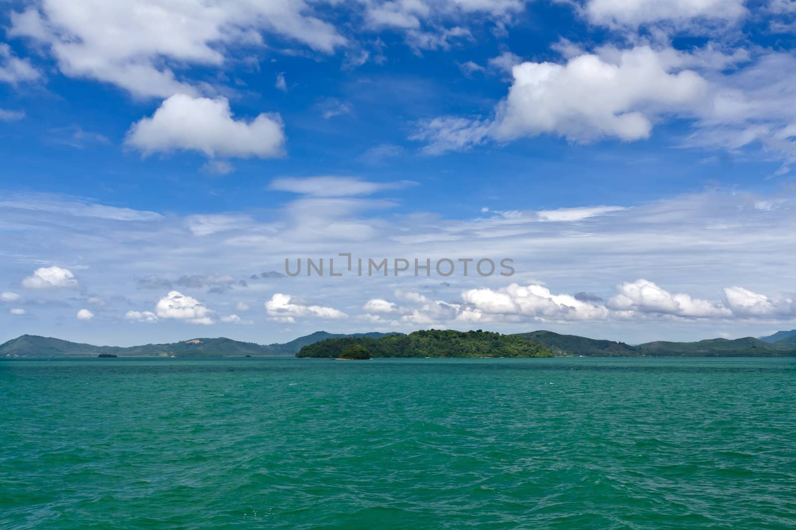 Landscape of palm island on the horizon in the Andaman Sea with blue sky and clouds