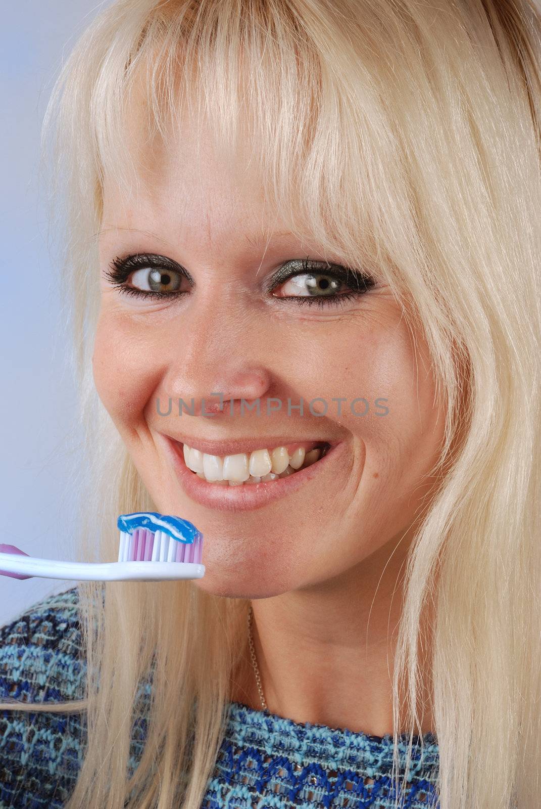 Young blonde woman brushing her teeth