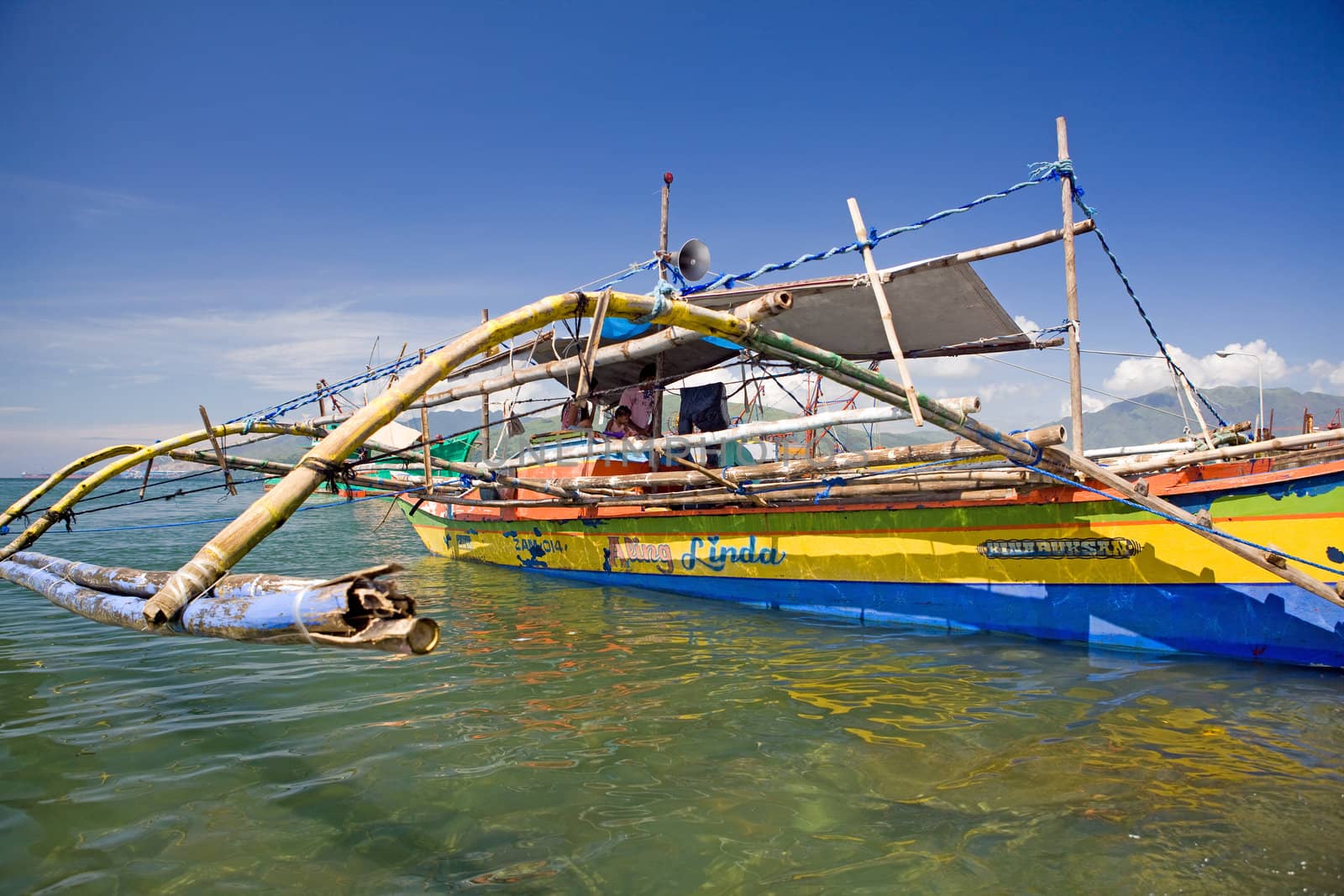 Filipino fishing family living onboard their outrigger canoe also called a pump boat and locally known as a bangka. Subic Town, Olongapo, Philippine Islands.