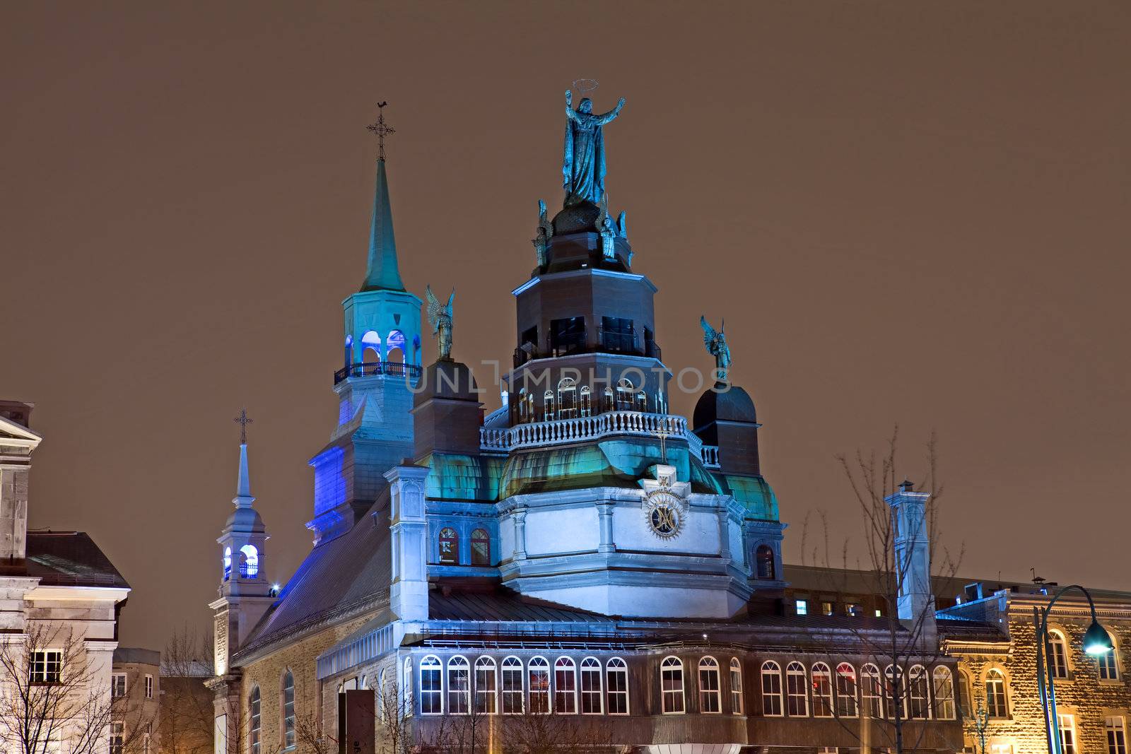 Night view of Notre Dame de Bon Secures Chapel in the Old Port section of Montreal, Quebec, Canada, 350 year old landmark built in 1771, also called The Sailor's Church, showing colorful blue lights, dome and statues on top of the church.