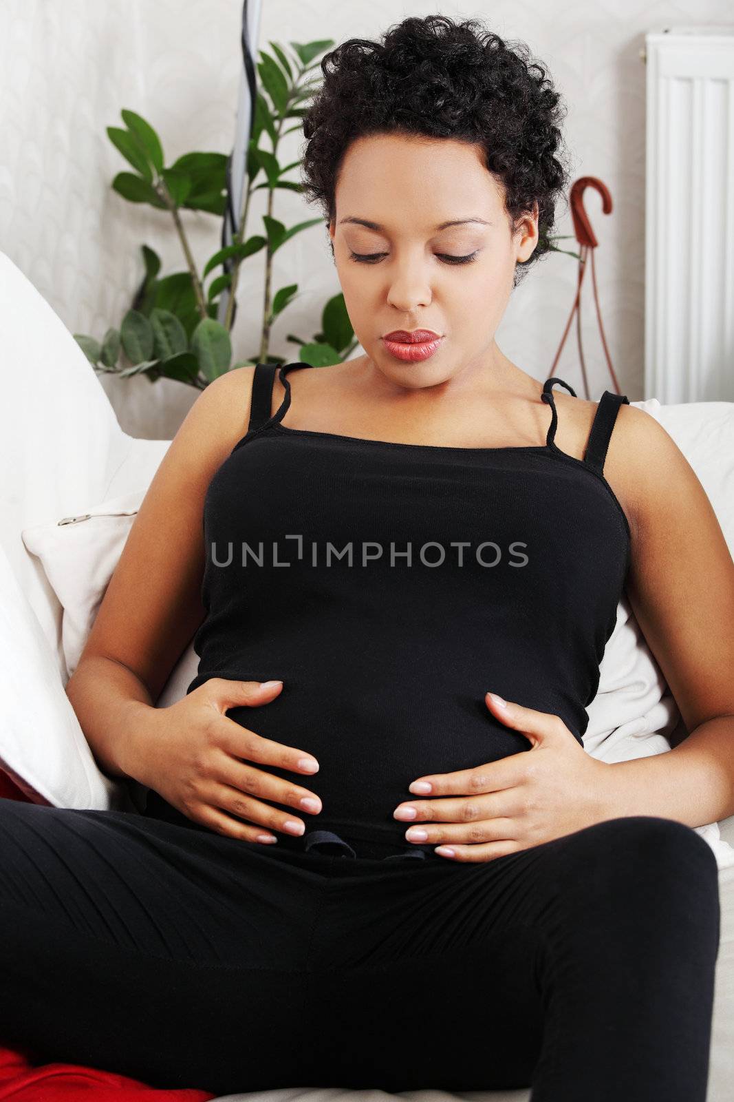 Young pregnant woman sitting on sofa