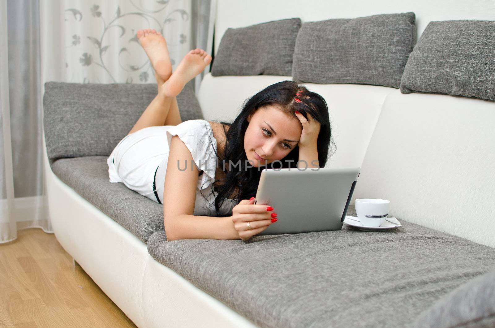 Brunette girl with tablet pc on the sofa.