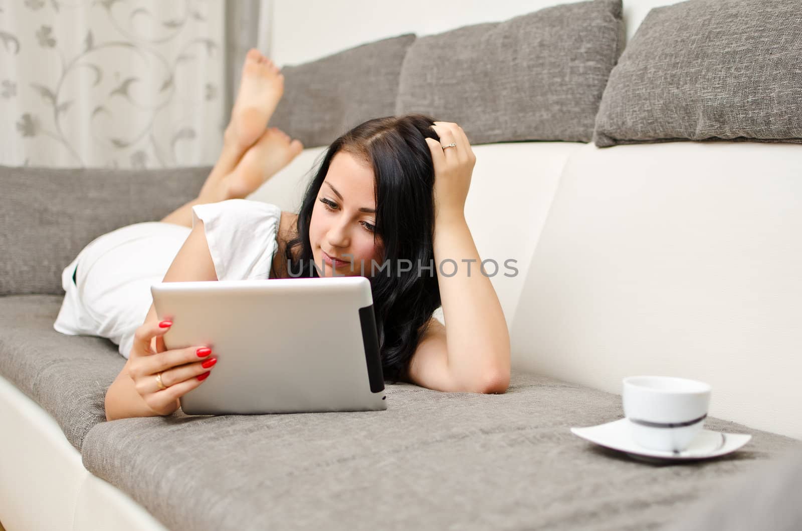 Brunette girl with tablet pc on the sofa.