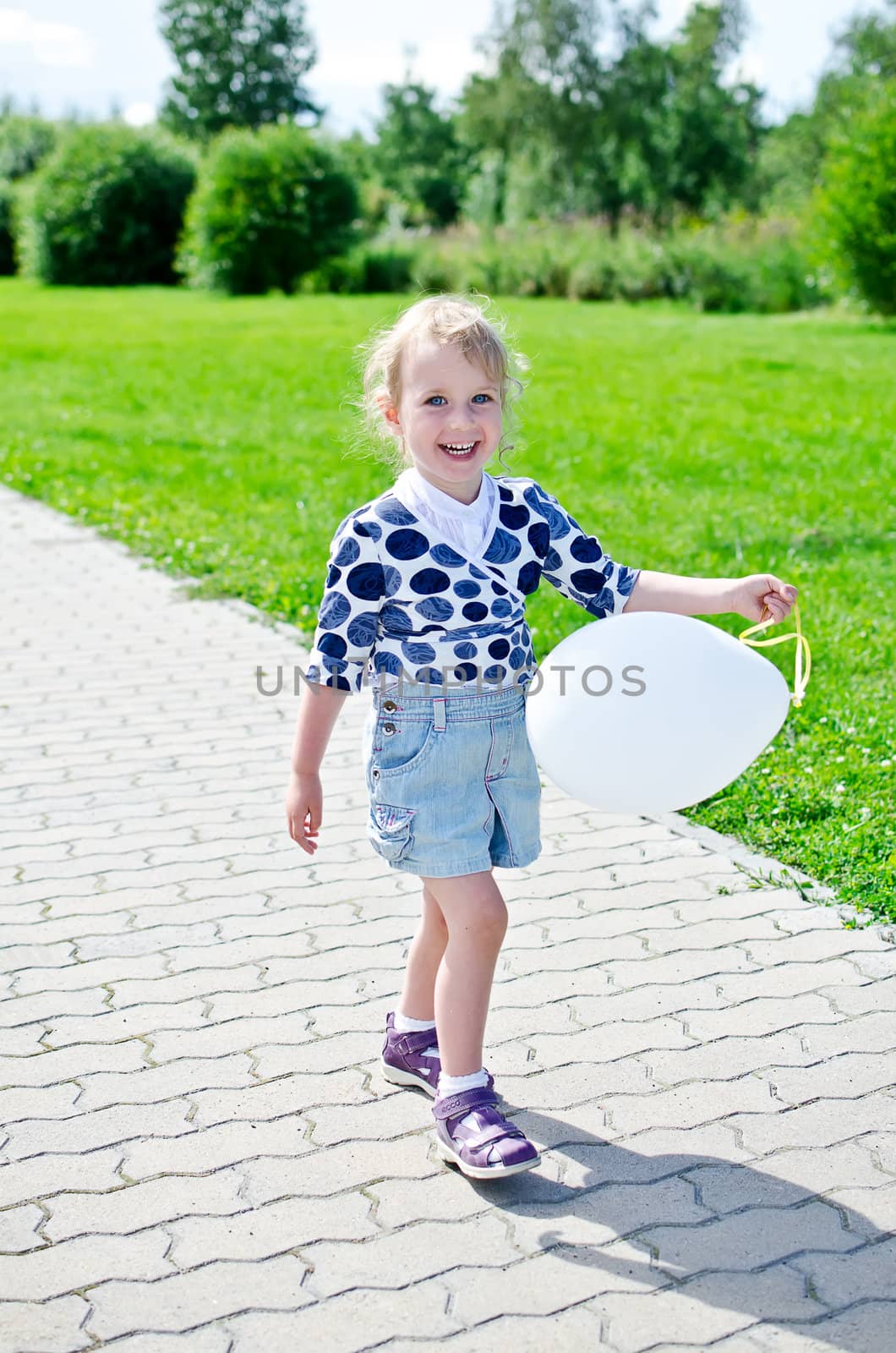 Smiling little girl with balloon in the park.