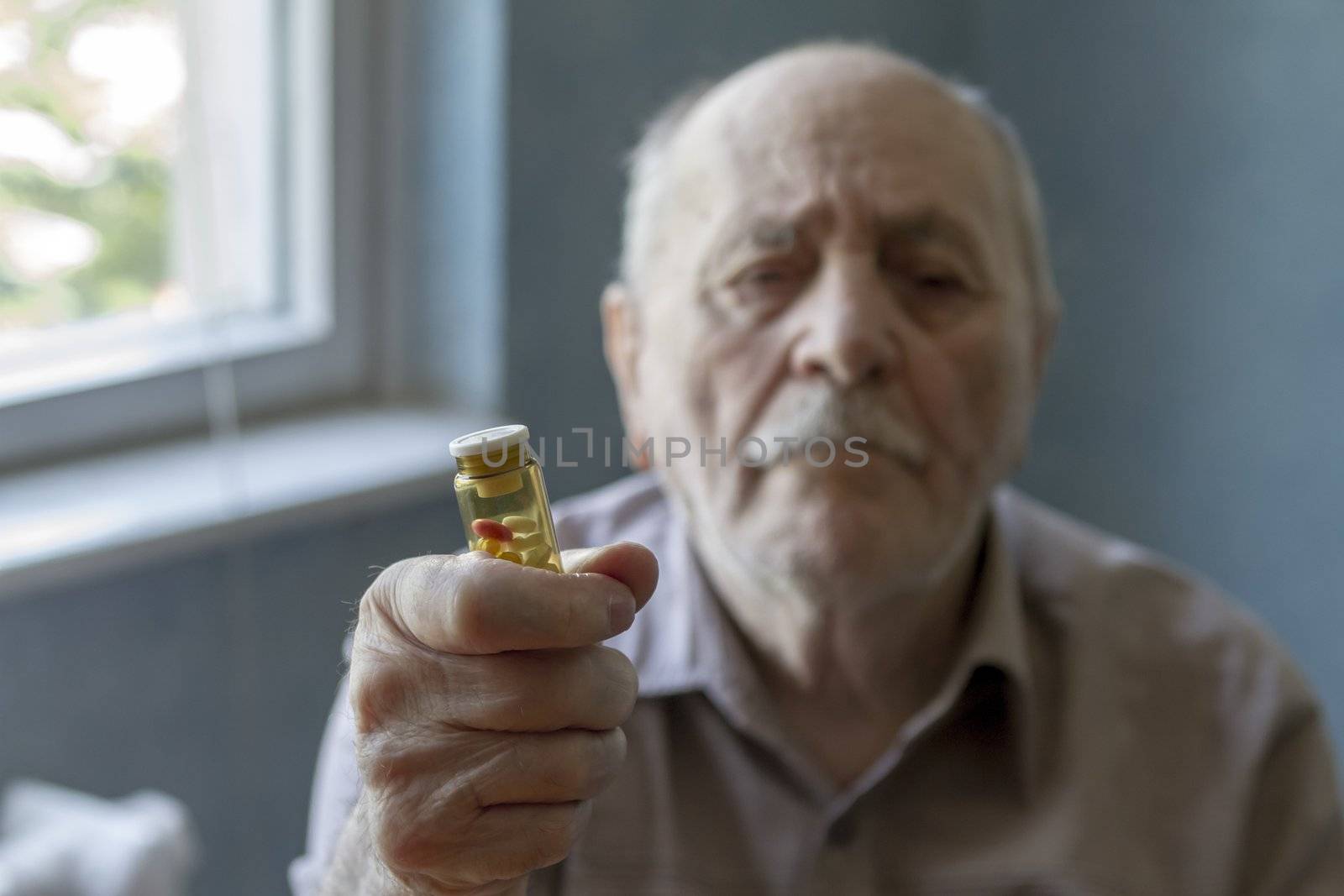 old man holding pills by manaemedia