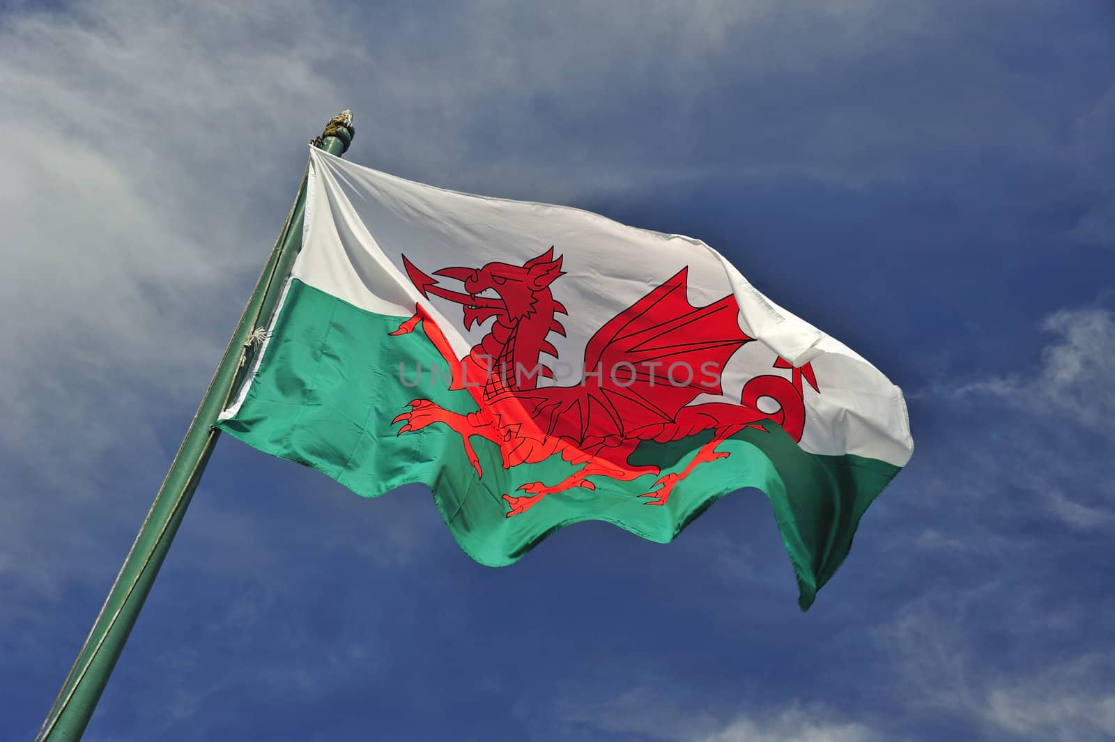 The Welsh flag against a blue sky. Motion blur at the tip of the flag. Space for text in the sky.