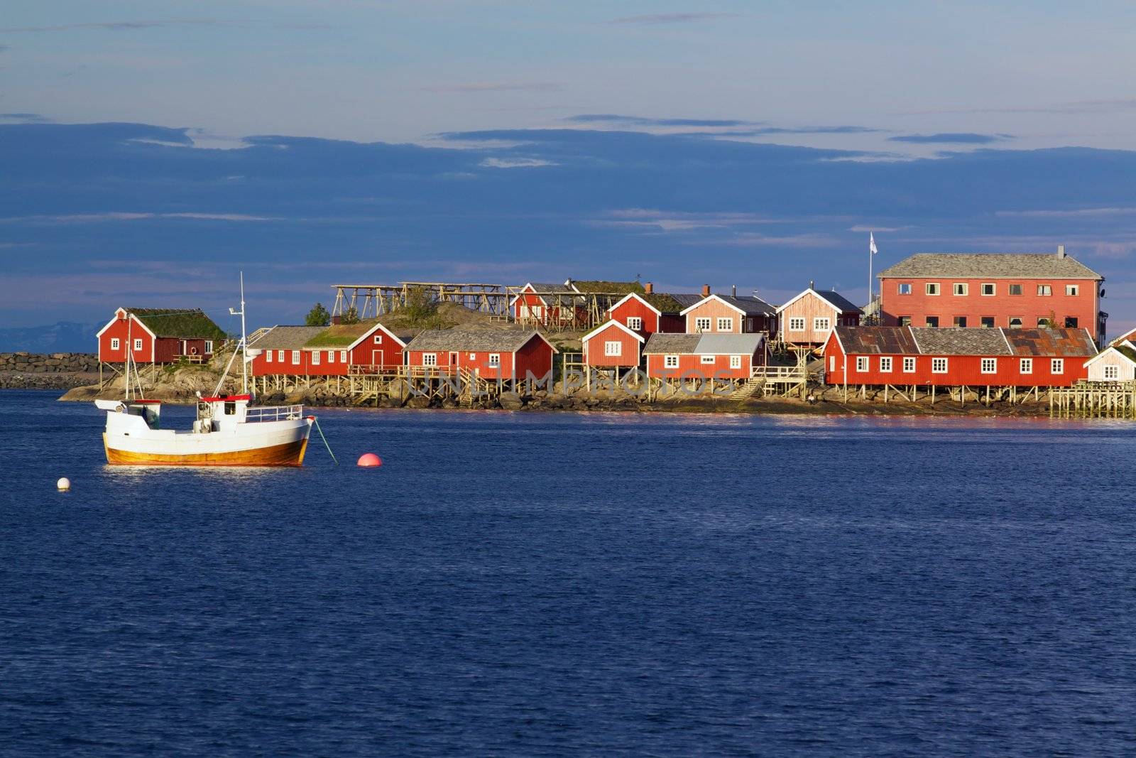 Red fishing rorbu huts and fishing boat in town of Reine on Lofoten islands