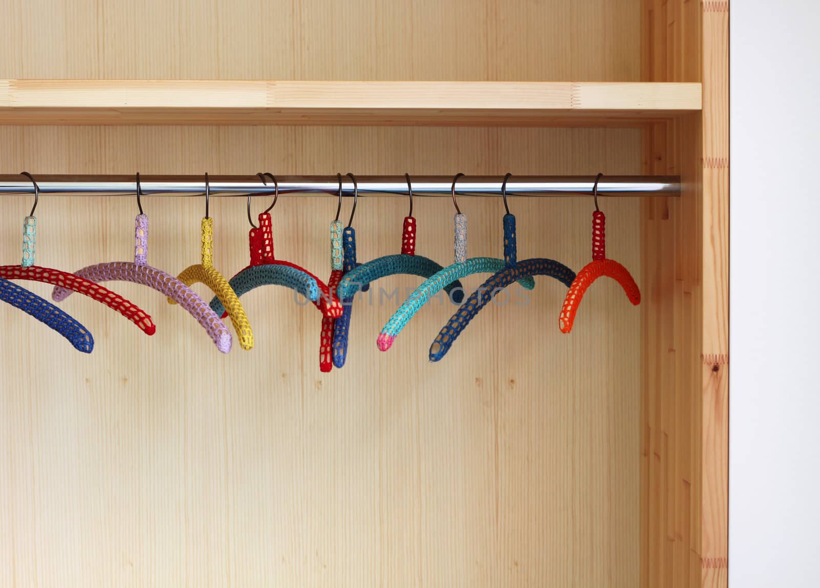 Colorful clothes hangers in closet by anterovium