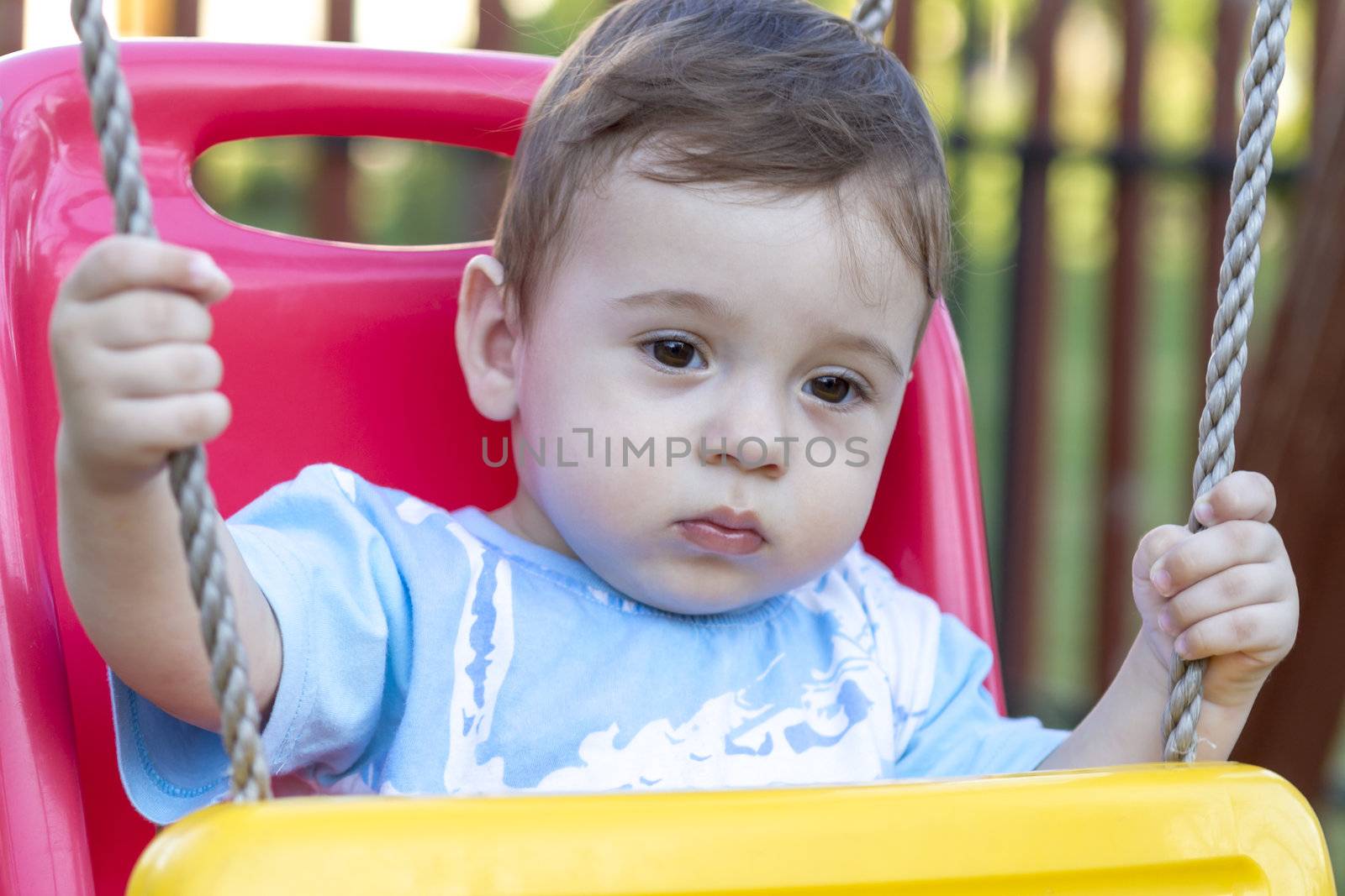 close-up of 9-month old baby boy  in a swing outdoors