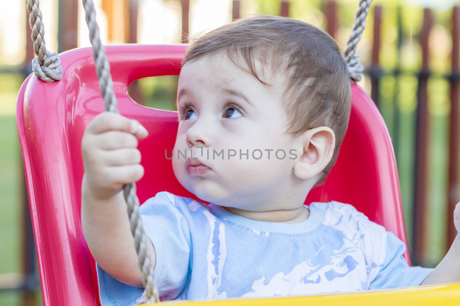 close-up of 9-month old baby boy  in a swing outdoors