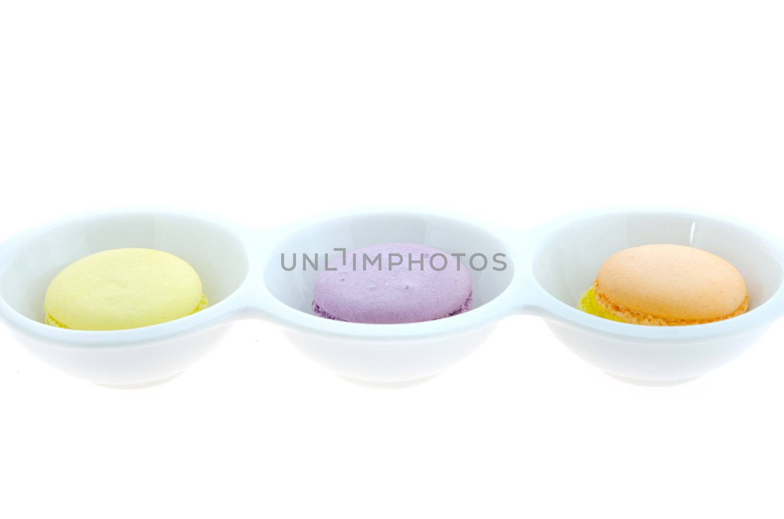 French macaroons in bowl on white background