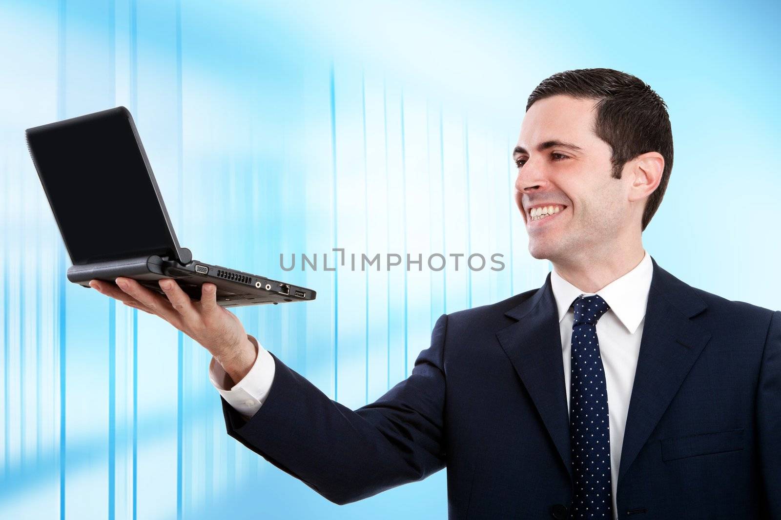 Handsome young business man in blue suit raising laptop in office.