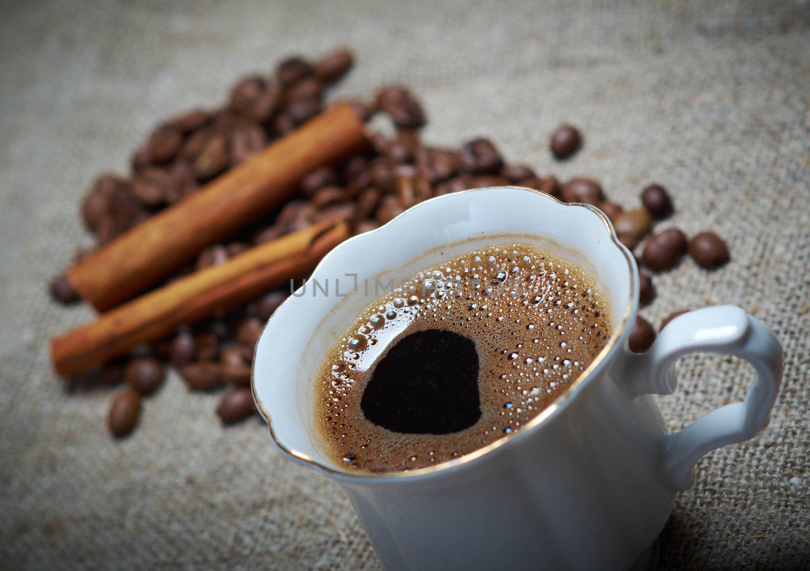 Coffee cup with cinnamon and coffee beans background