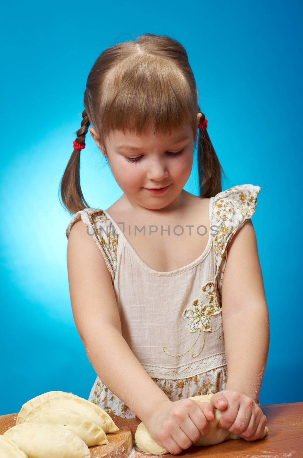 Smiling little girl kneading dough at kitchen with baking a pie