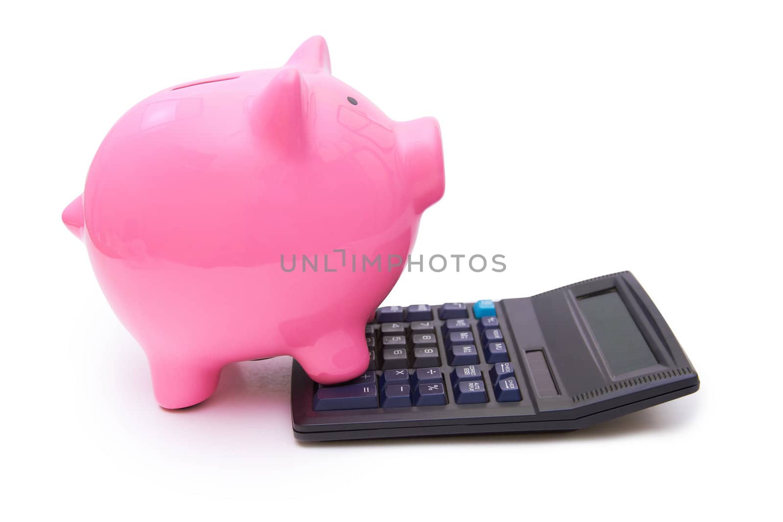 Pink piggy bank is on the calculator on white background.