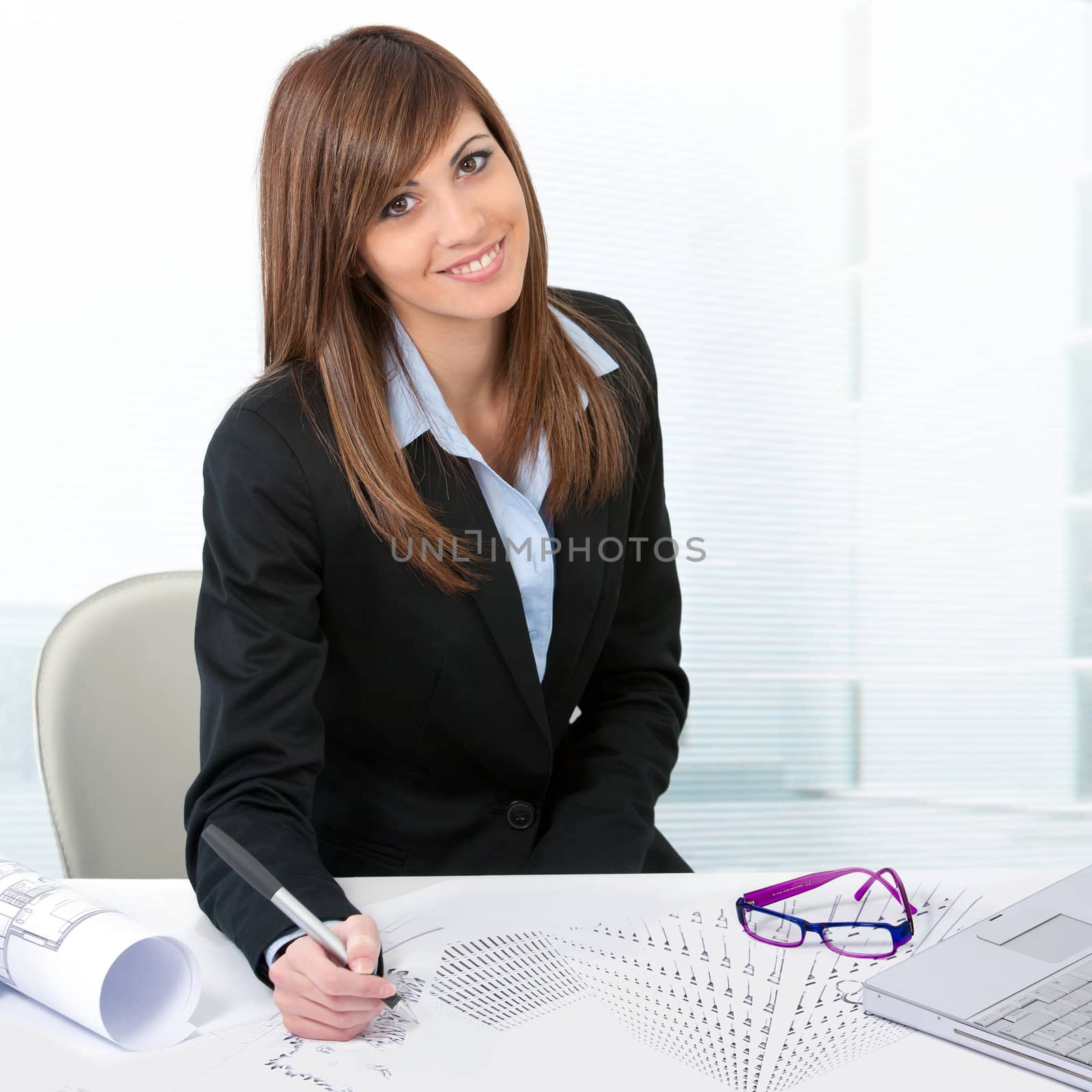 Portrait of Attractive young business woman at desk with plans.