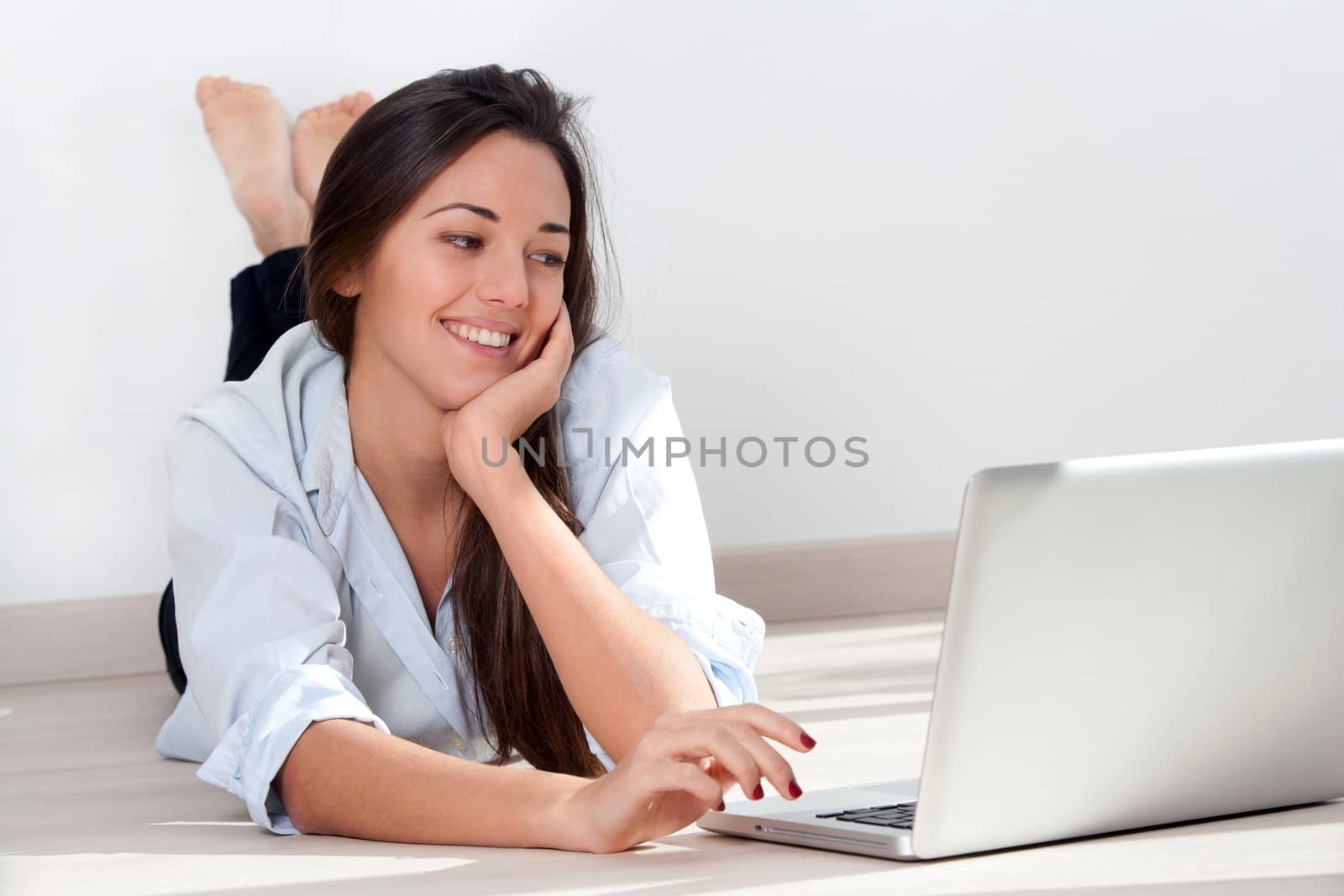 Young woman laying on floor with laptop by karelnoppe