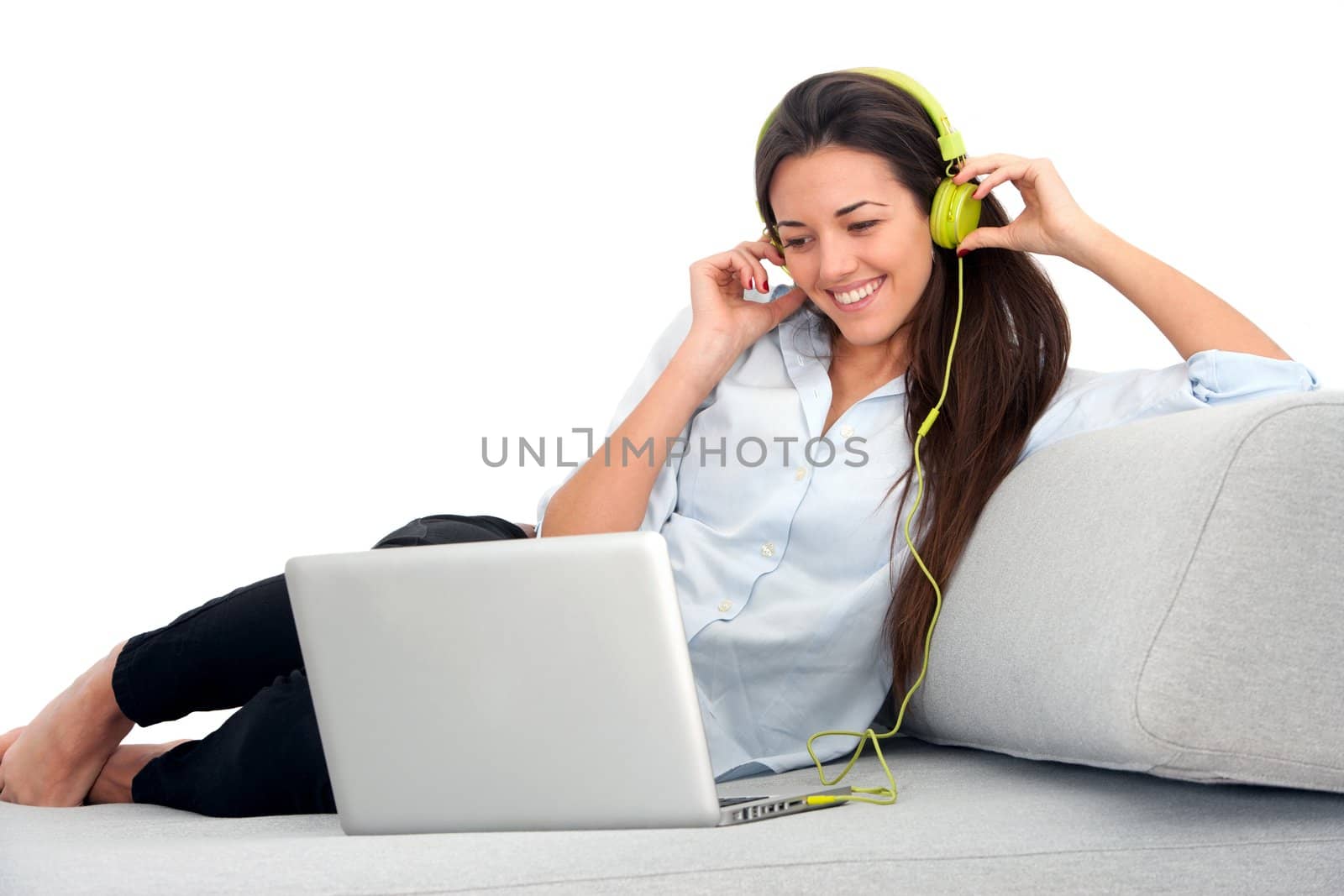 Young attractive woman sitting on couch with laptop and earphones.
