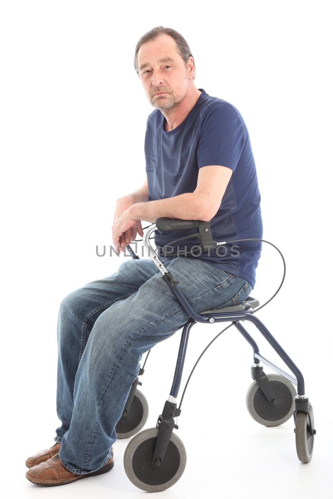 Depressed man sitting on a medical walker taking a break from the struggle of moving with the aid of the walker 