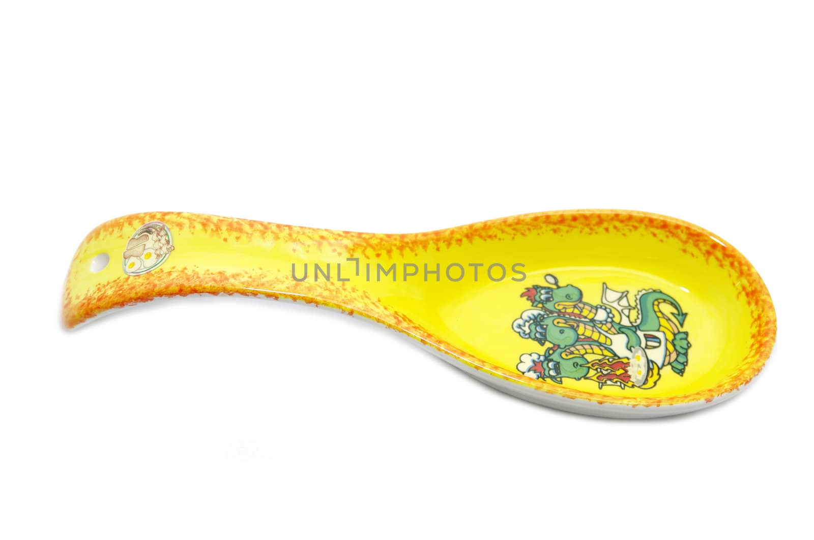 yellow spoon with ceramic figures of a dragon on a white background