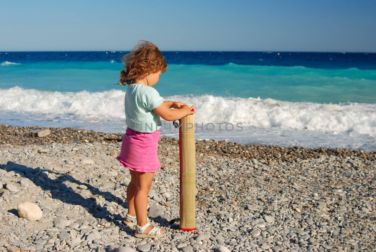 A girl lays on a beach mat.