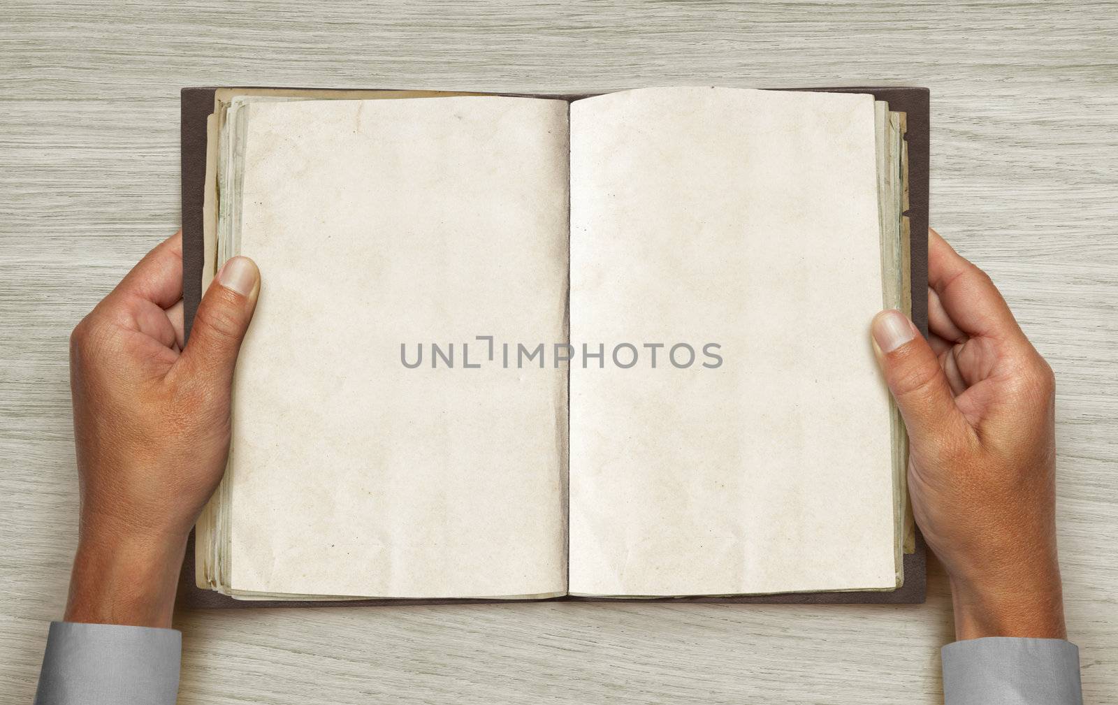 hands and opened vintage book over table