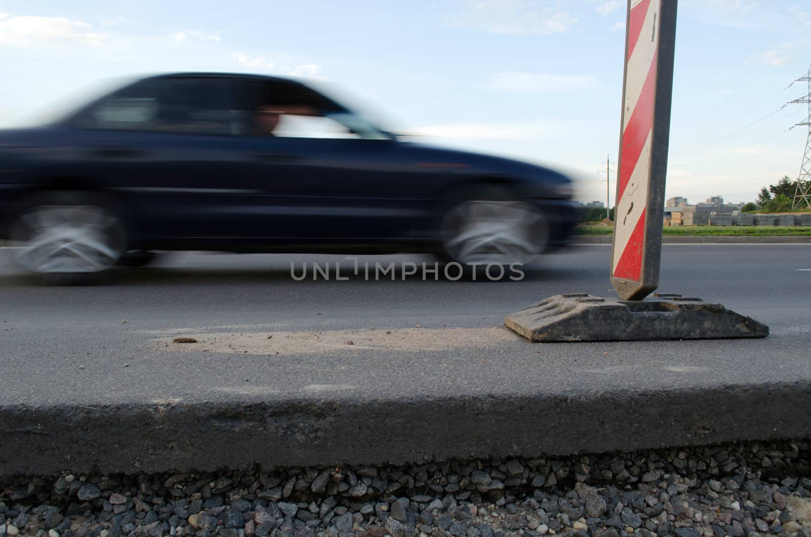 Road asphalt pavement thickness passing car and warning sign.