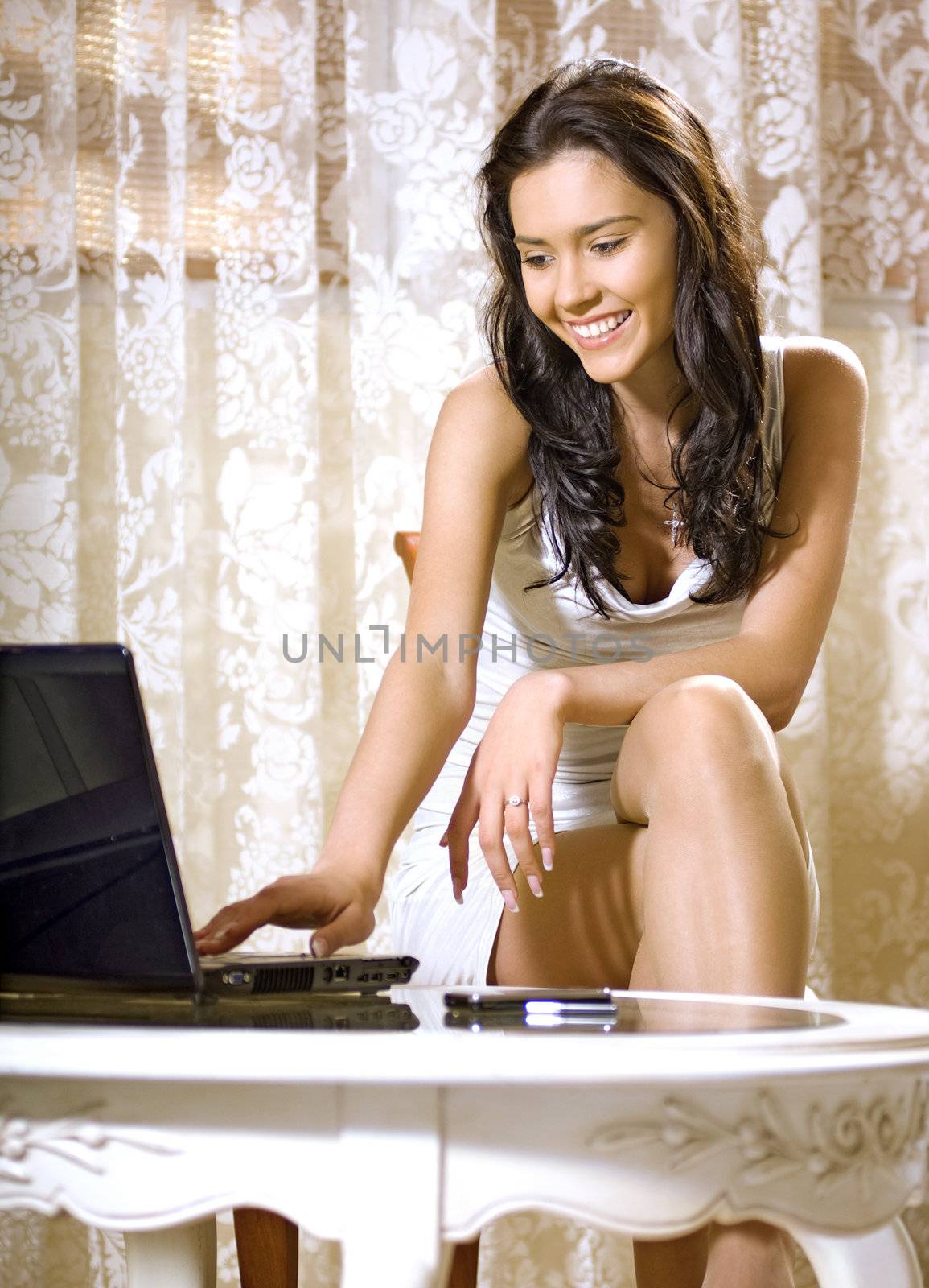 happy young girl sits at occasional table and works with notebook computer