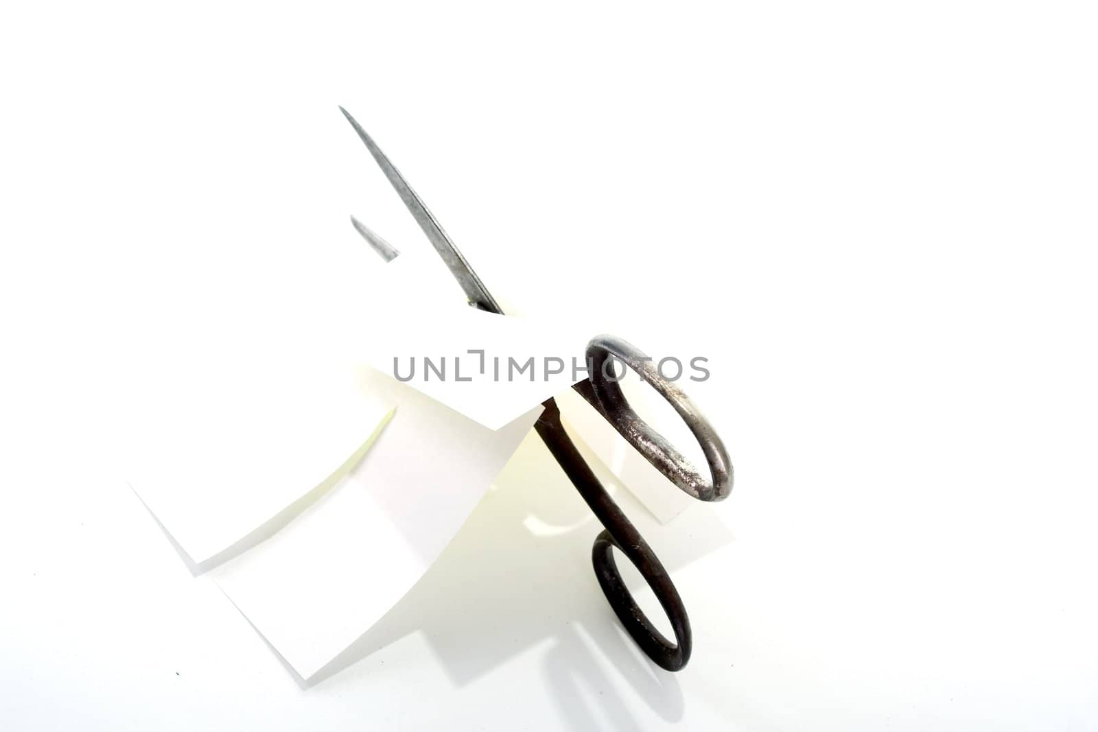 Old rusty steel scissors cut paper on white background