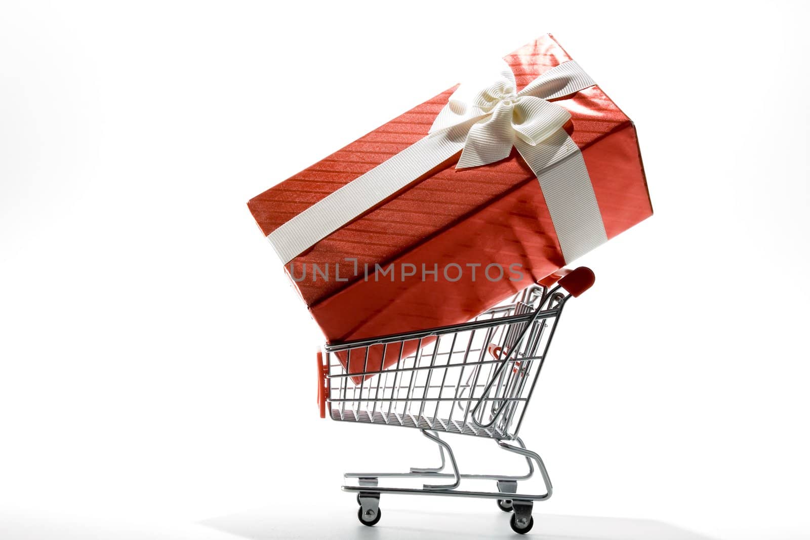 shopping cart with gift box wrapped in colored paper and ribbon on white background