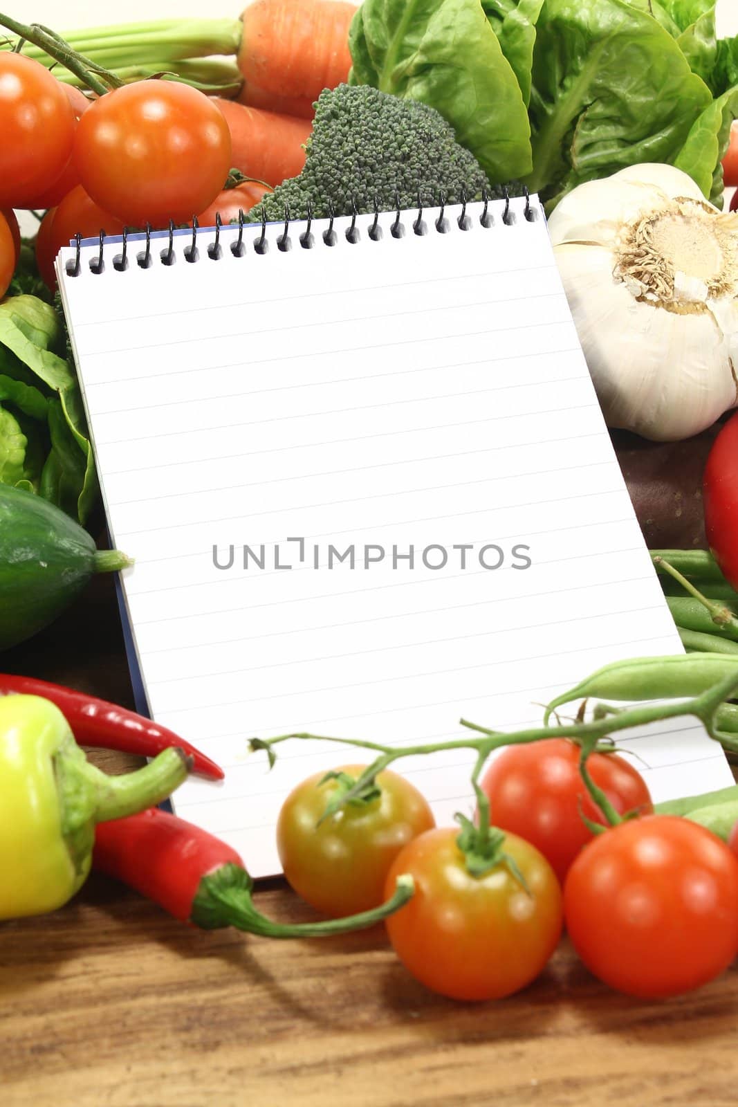 Ruled shopping list with vegetables on a wooden background