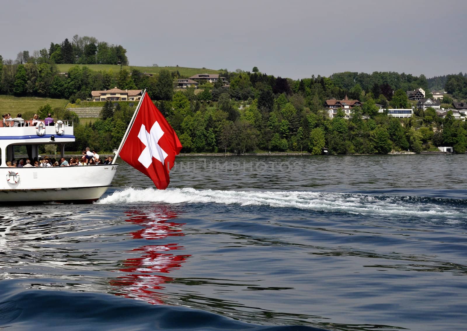 Swiss flag in boat, during summer. Lake and mountains in the back.