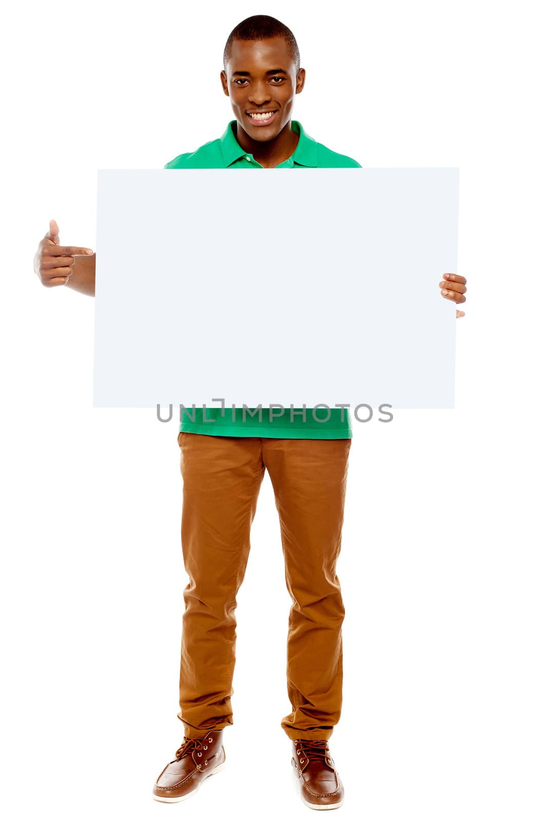 Full length portrait of casual young guy pointing towards placard