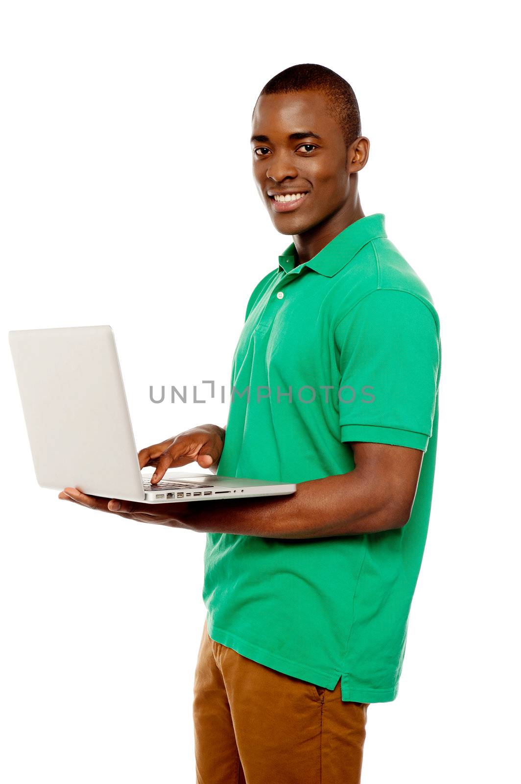 Cool teenage guy surfing internet on laptop and smiling at camera
