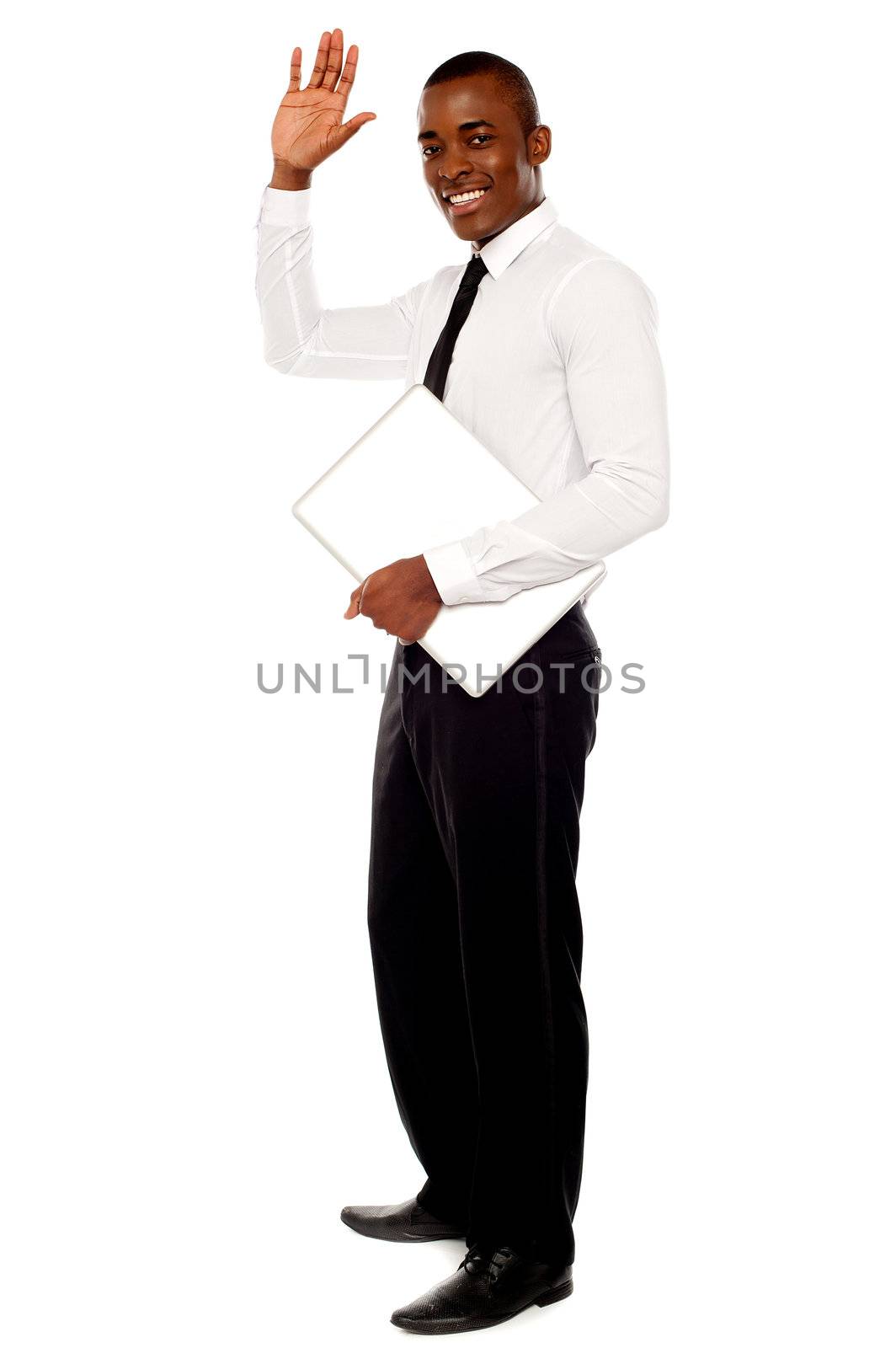 Full length portrait of handsome african businessman waving hand and holding laptop