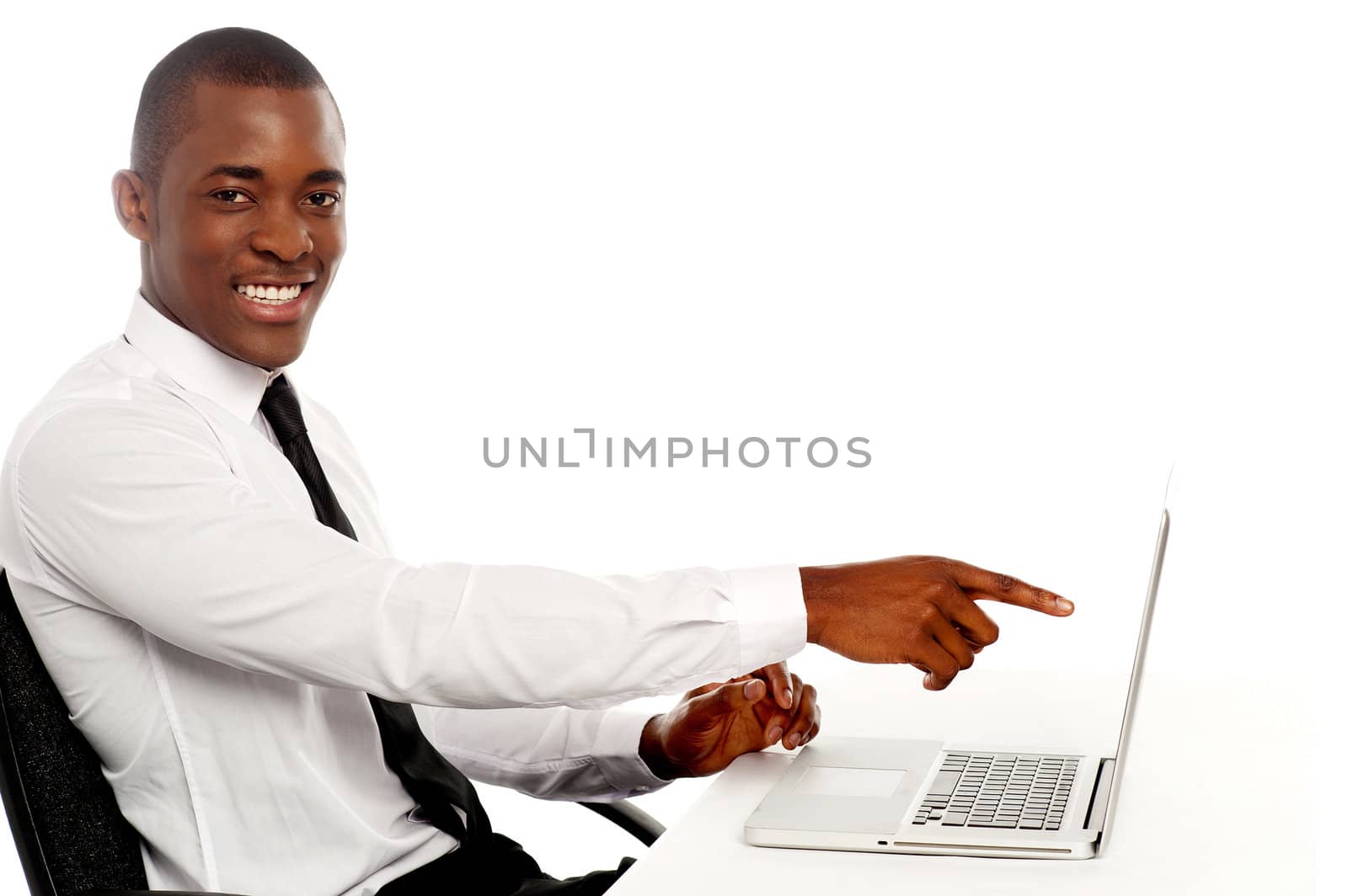 Smiling young african indicating on laptop screen sitting on chair in office