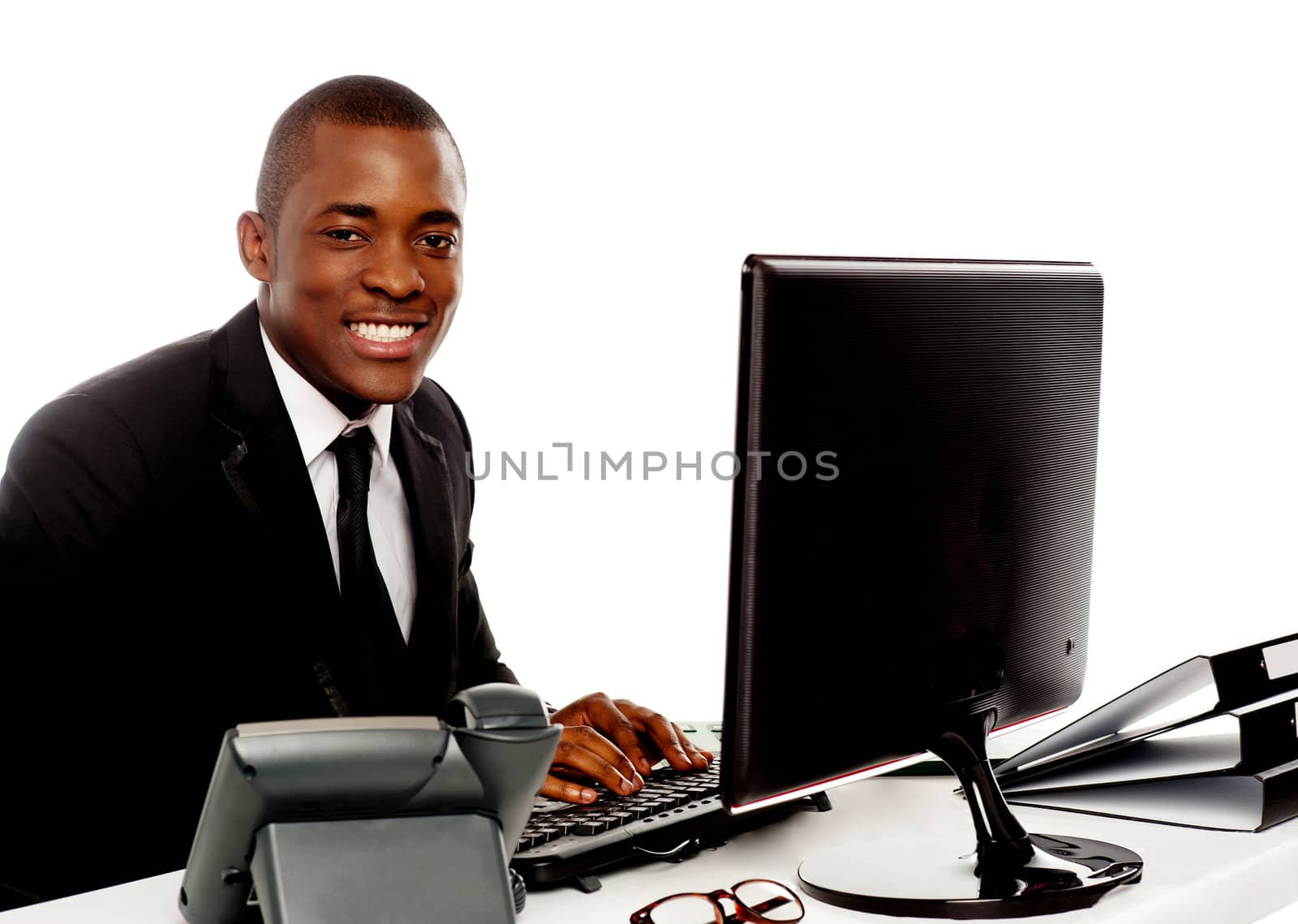 Smiling young corporate man using computer looking at camera