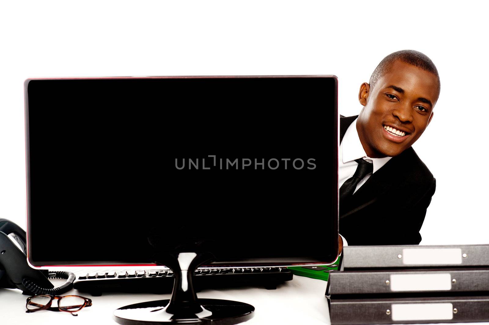 Businessman peeping from behind lcd monitor and enjoying himself during work hours
